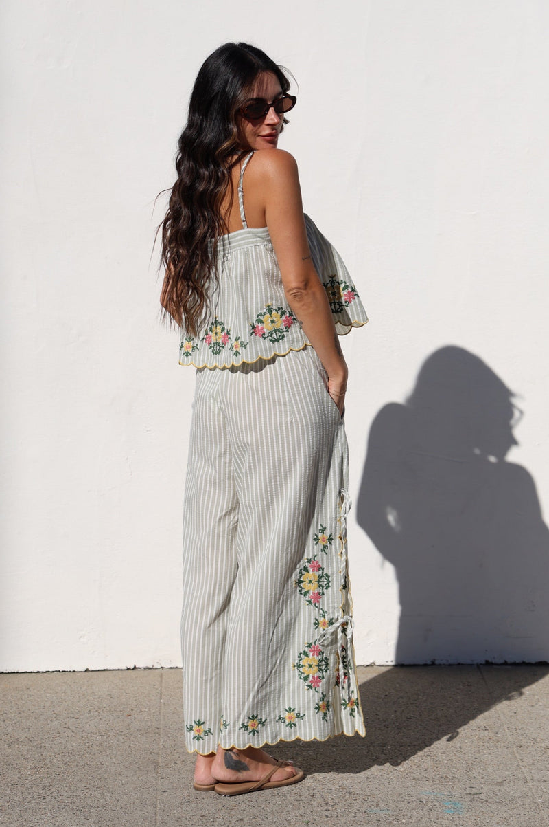 Woman wearing a floral dress standing against a white wall.