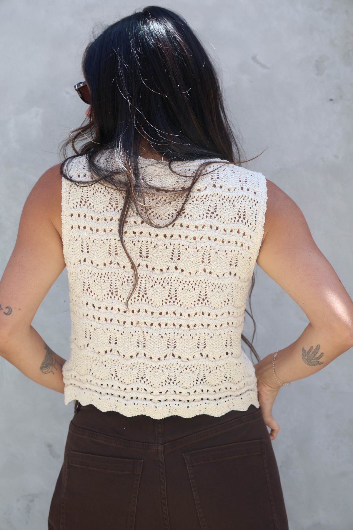 Person wearing a beige crochet top against a gray background