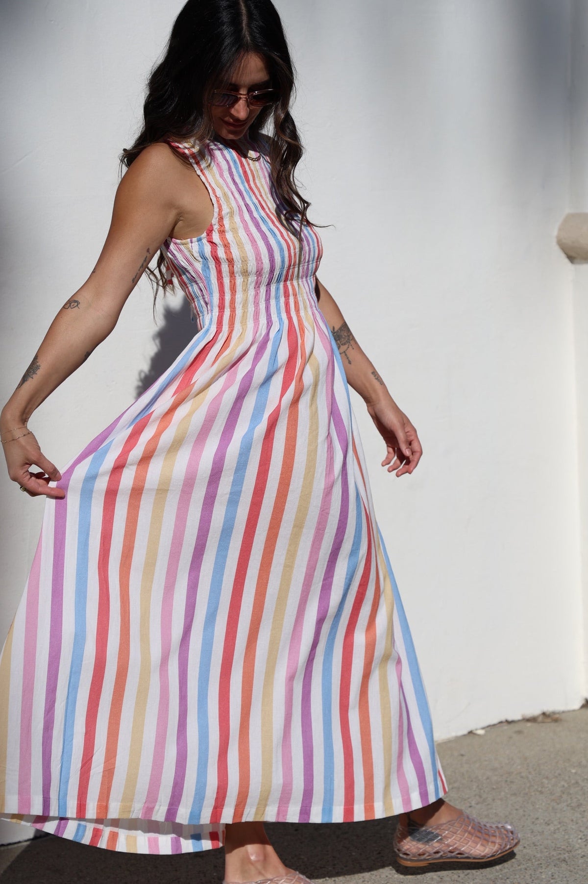 Woman wearing a colorful striped dress against a plain background