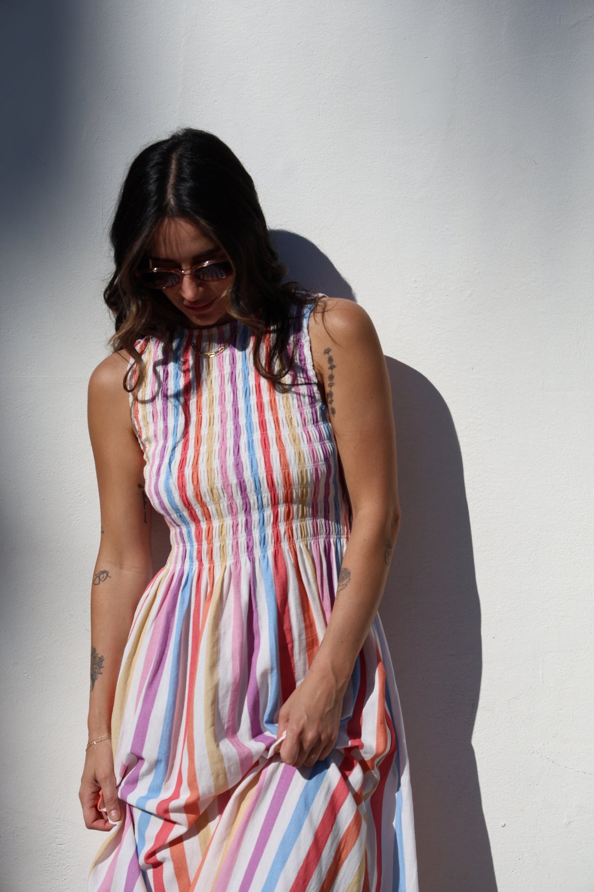 Woman wearing a colorful striped dress against a white wall