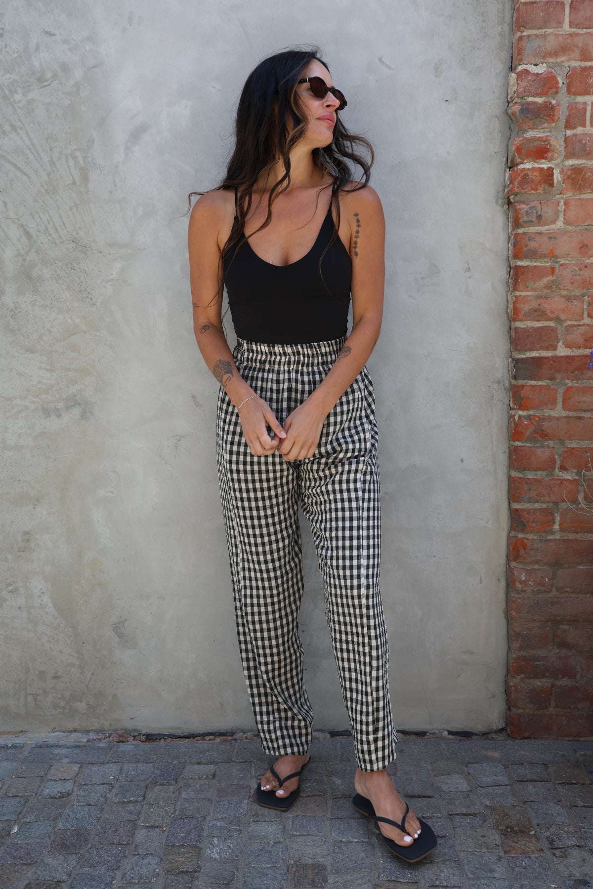Person wearing black and white checkered pants standing against a plain wall.