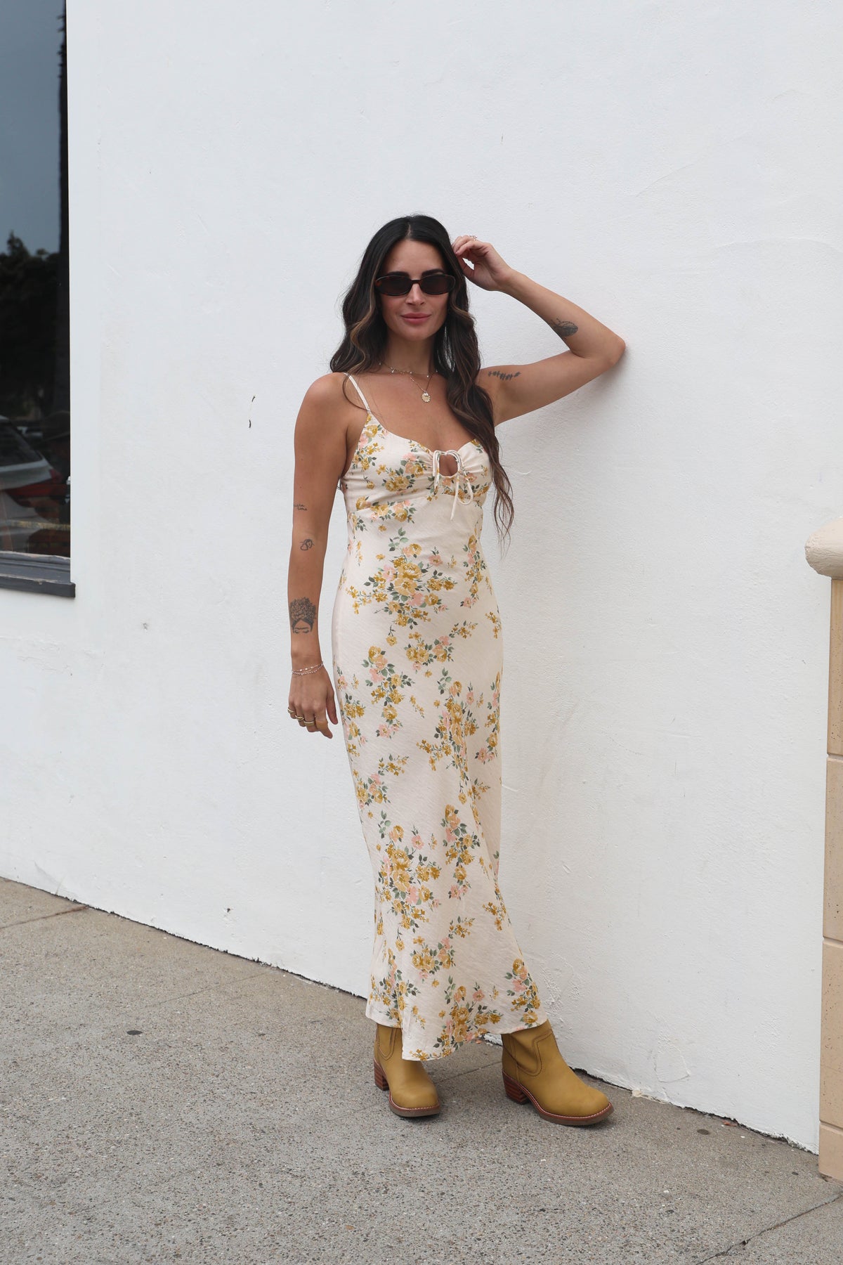 Woman in a floral dress standing against a white wall