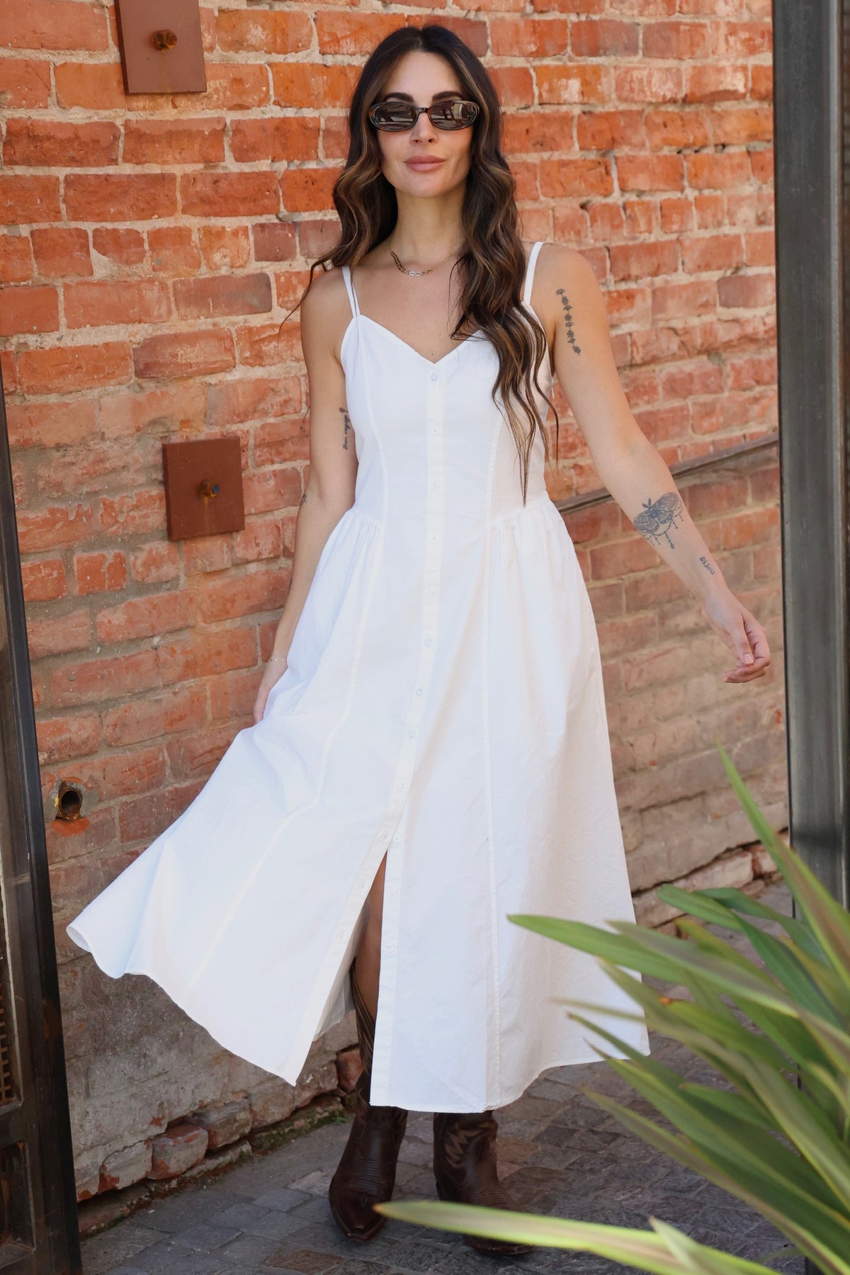 Woman wearing a white dress with a brick wall background