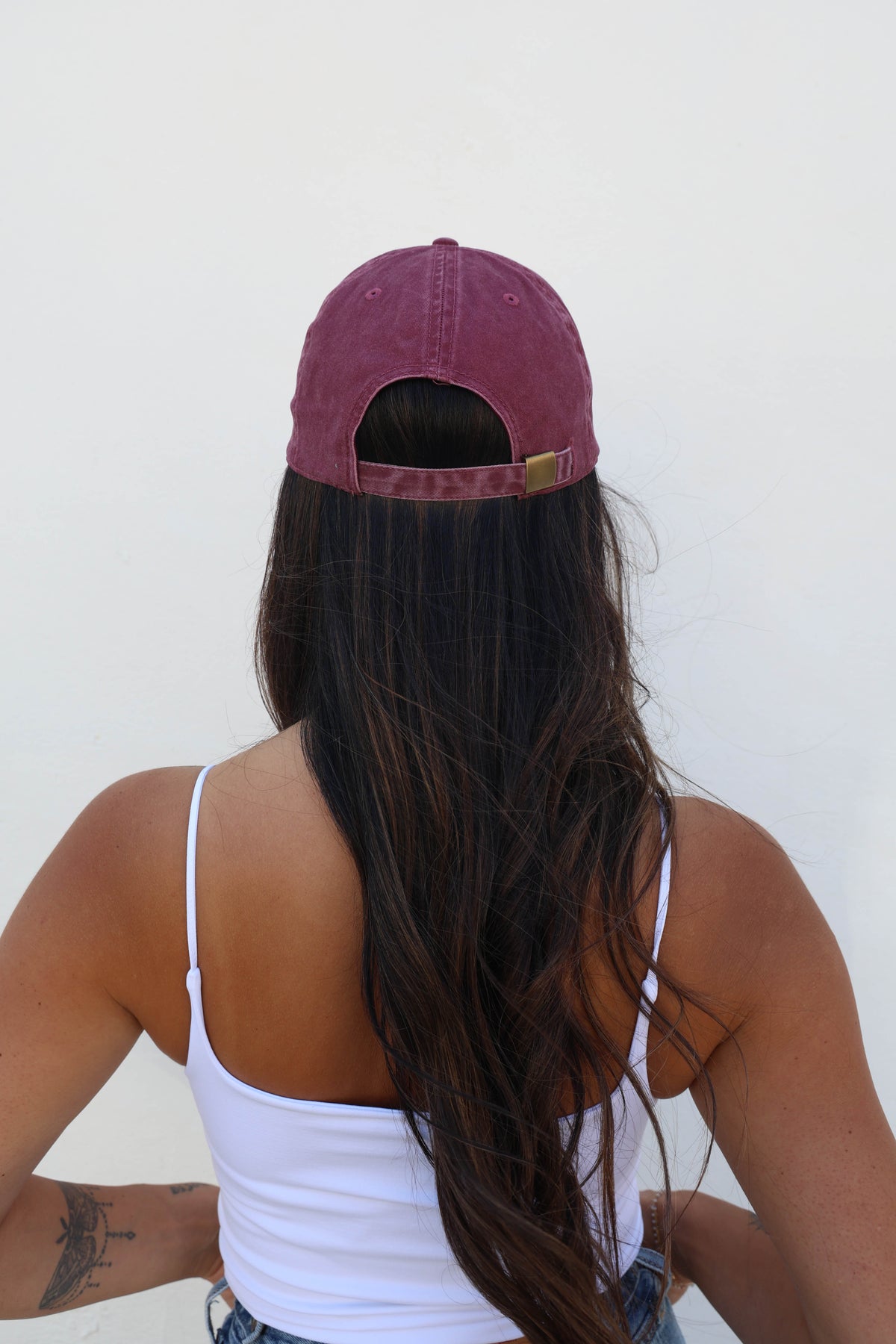 Woman wearing a hat against a white wall