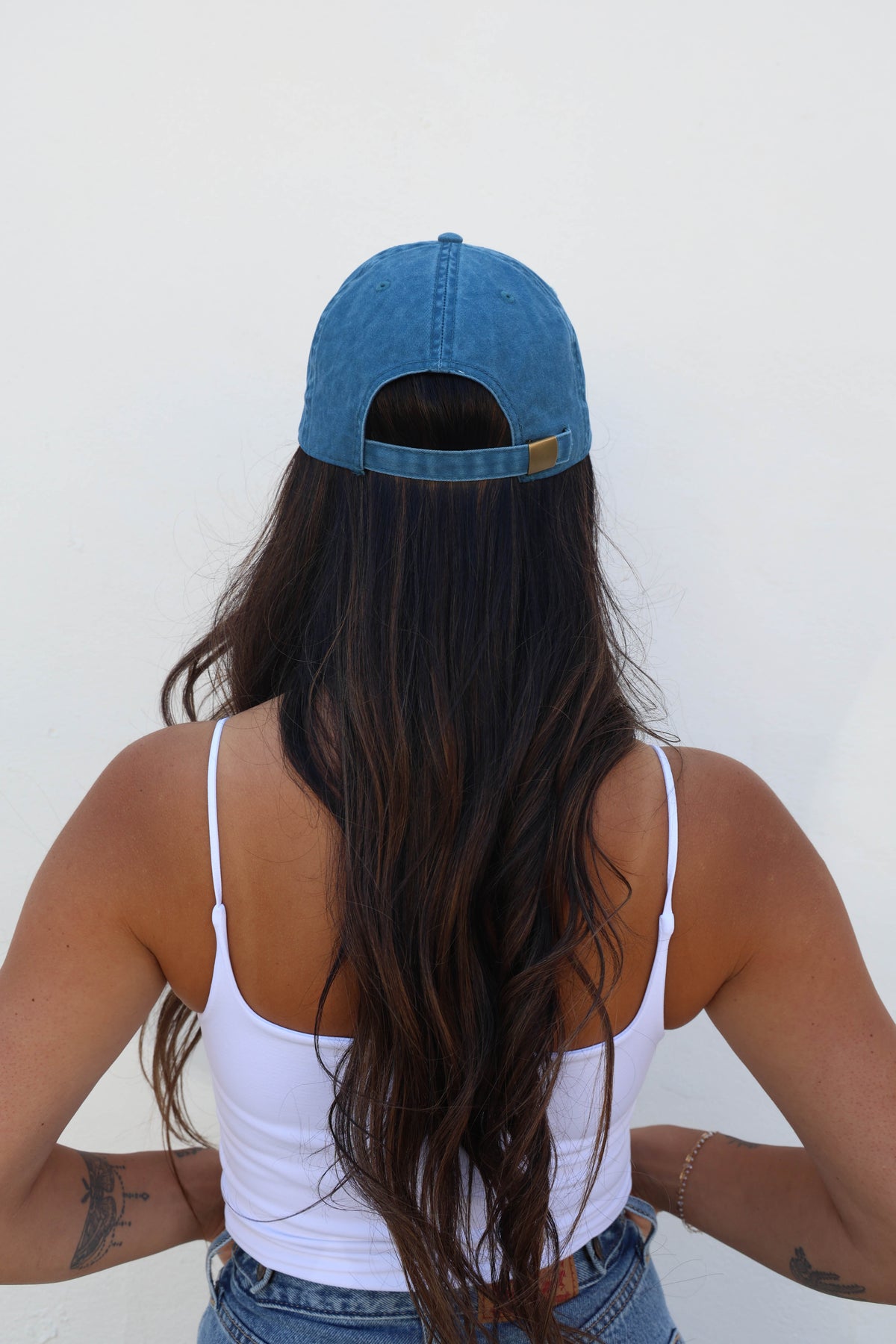 Woman wearing a hat against a white wall
