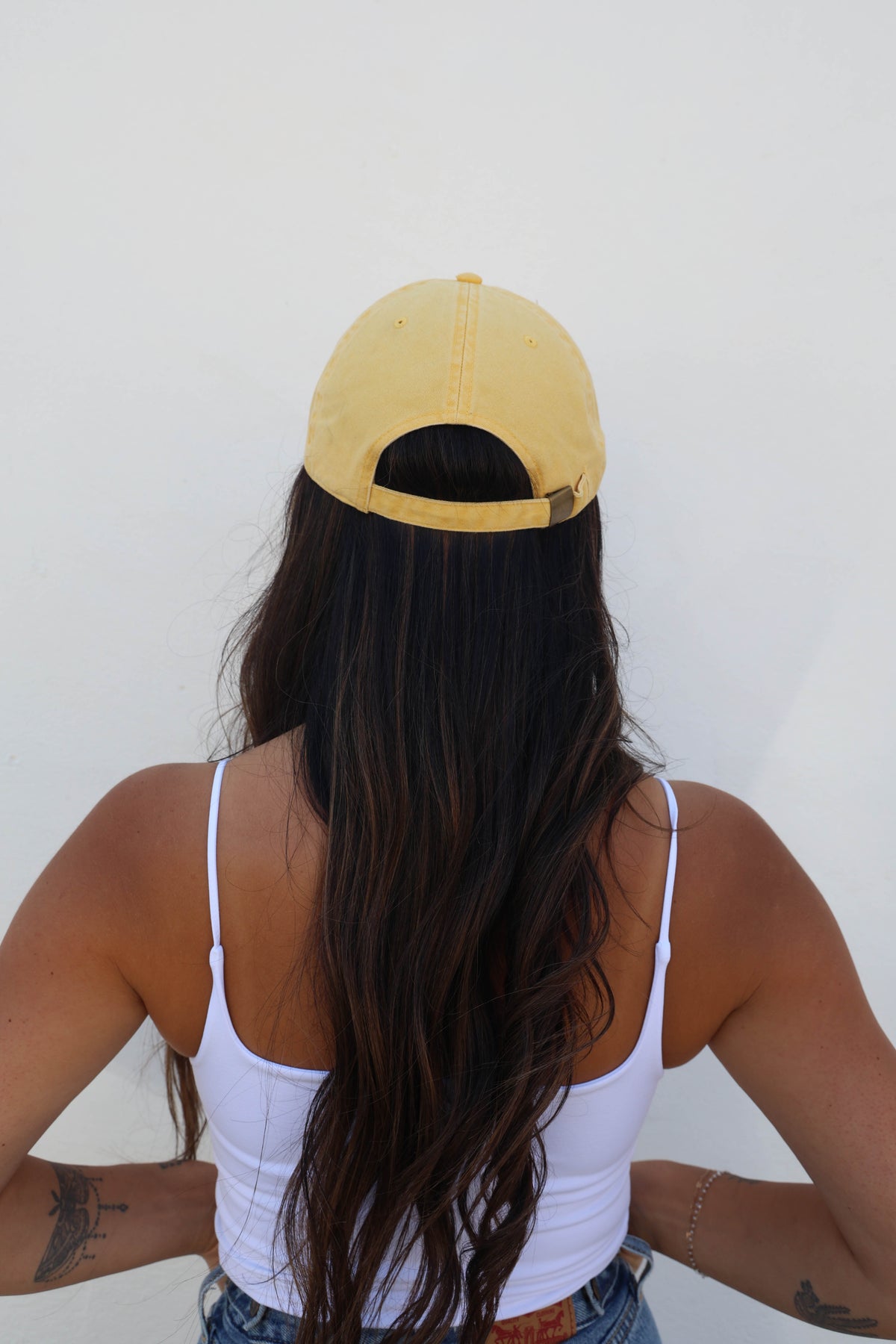 Woman wearing a hat against a white wall