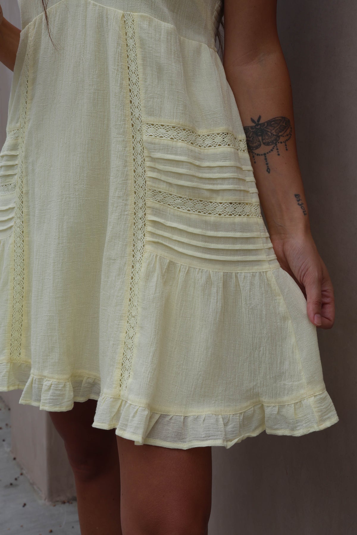 Light yellow dress with lace details worn by a person against a neutral background