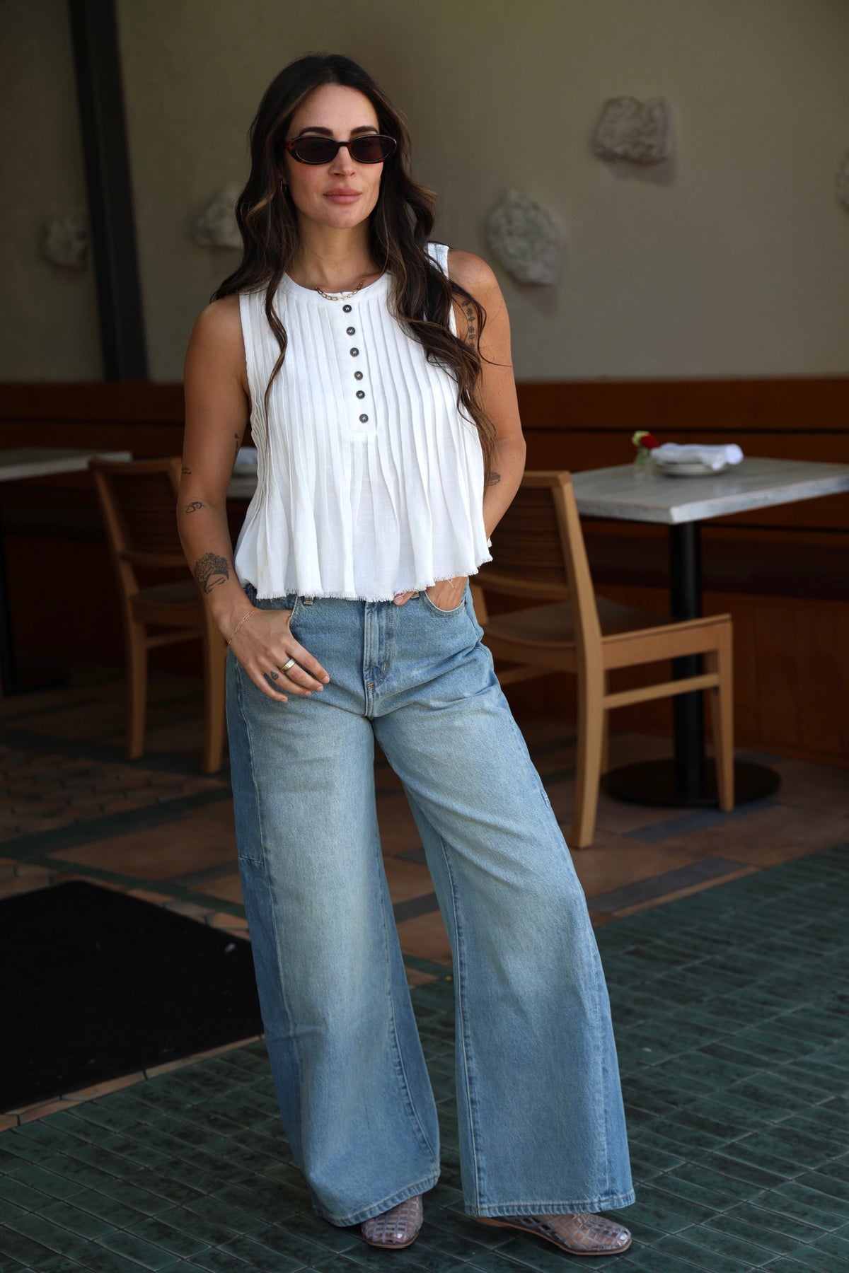 Woman wearing a white blouse and blue jeans in an indoor setting