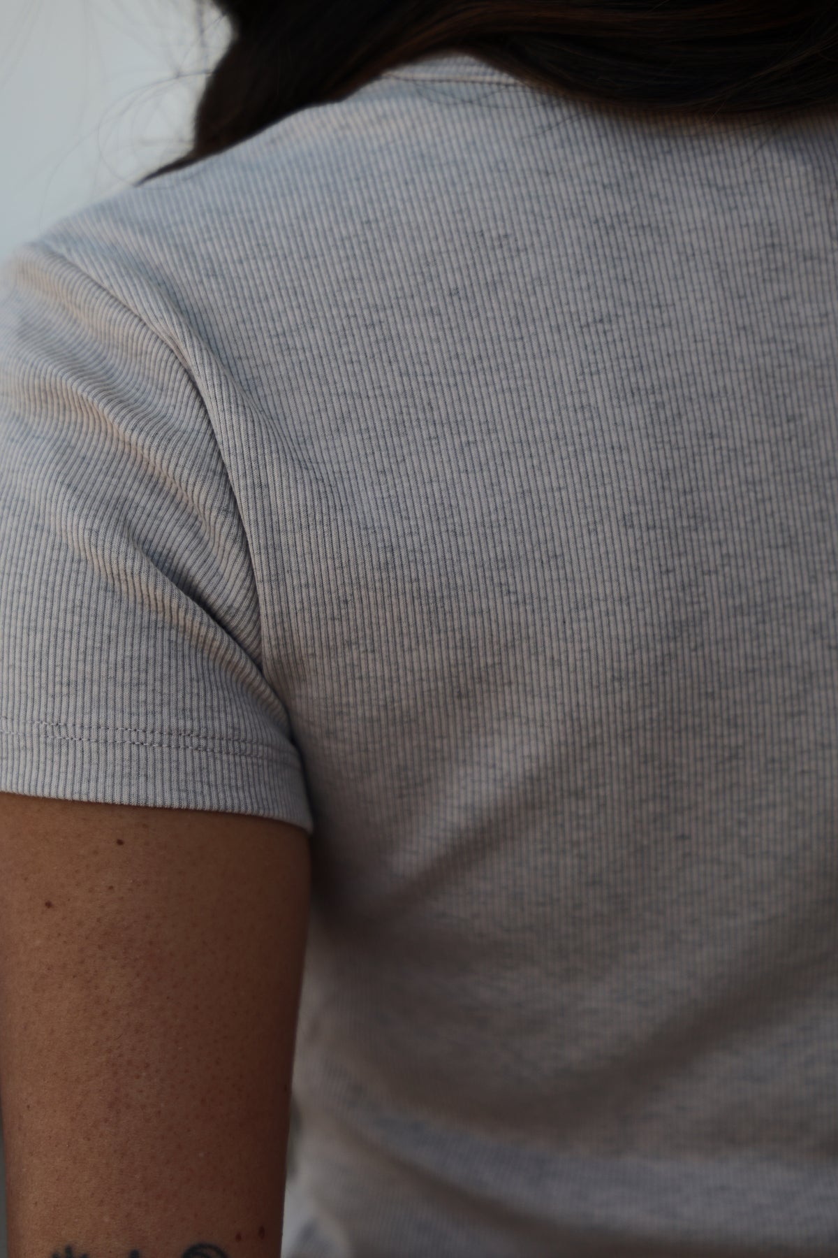 Close-up of a person wearing a gray t-shirt with a blurred background