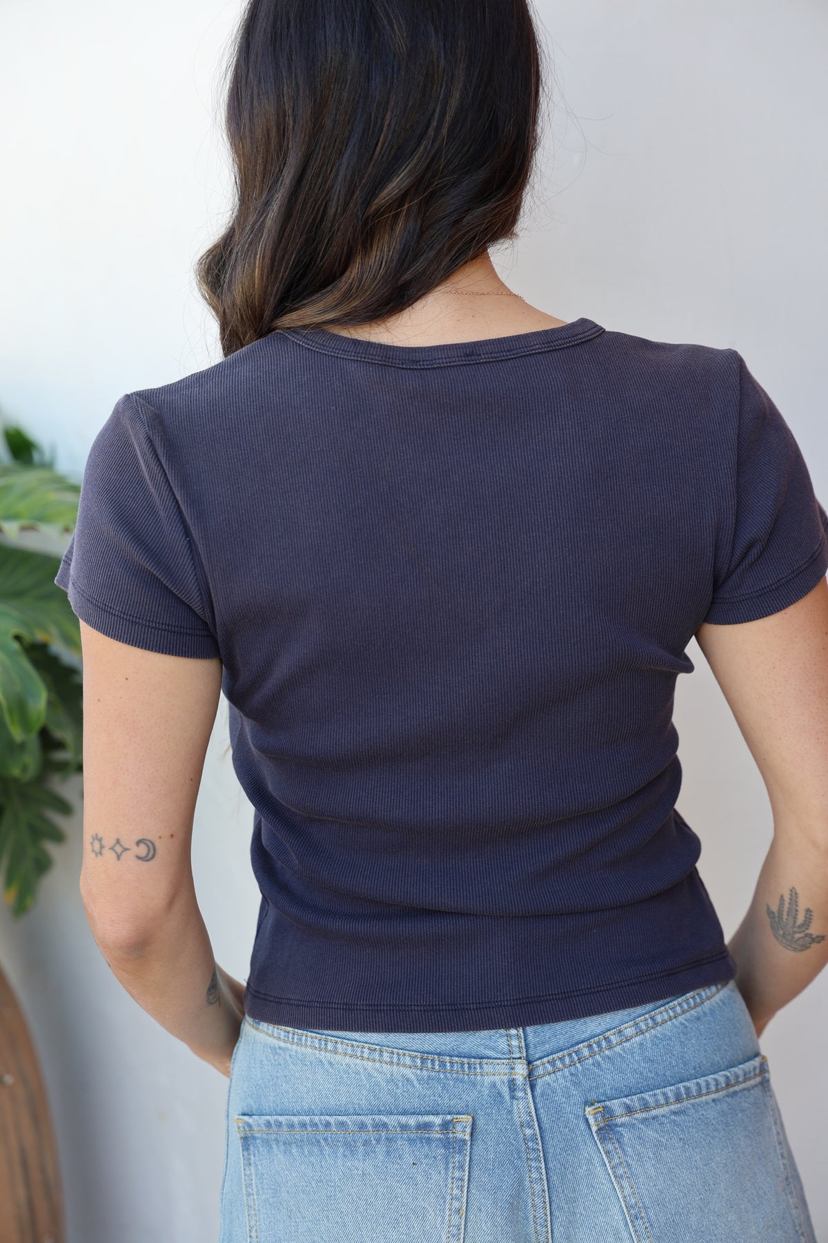Person wearing a navy blue t-shirt and light blue jeans against a plain background