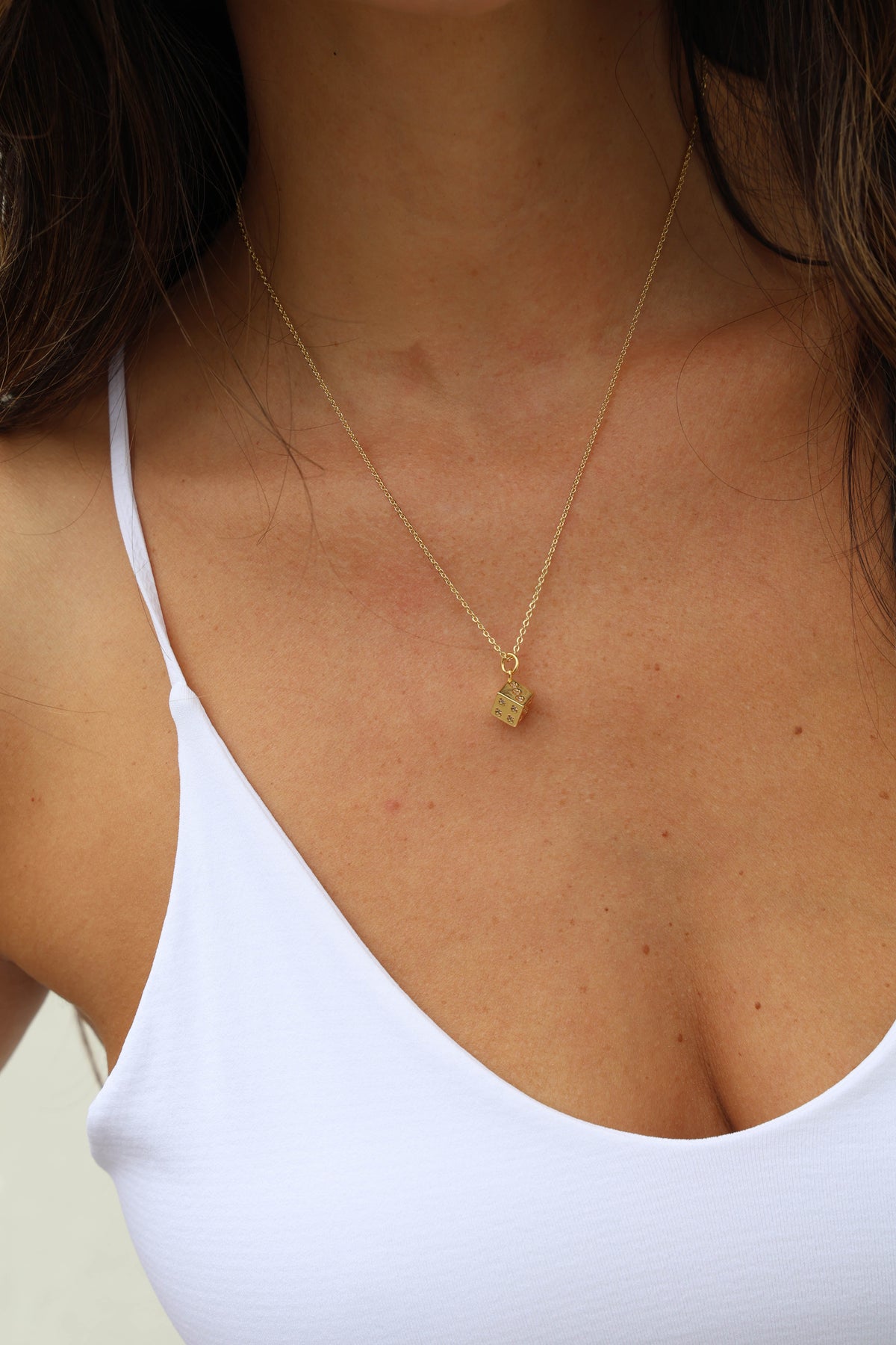 Close-up of a person wearing a gold necklace with a small pendant.