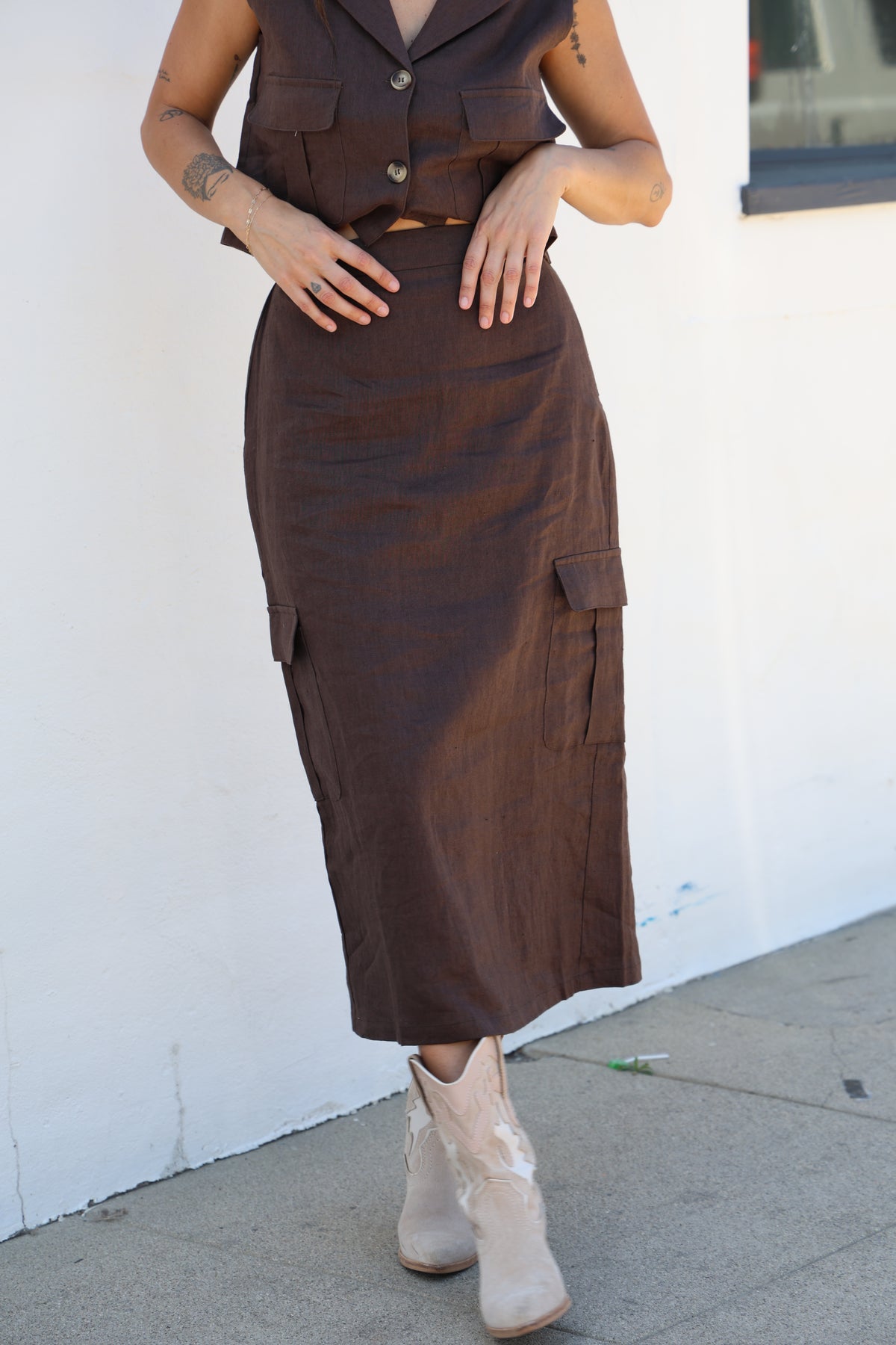 Person wearing a brown outfit with beige shoes on a white background