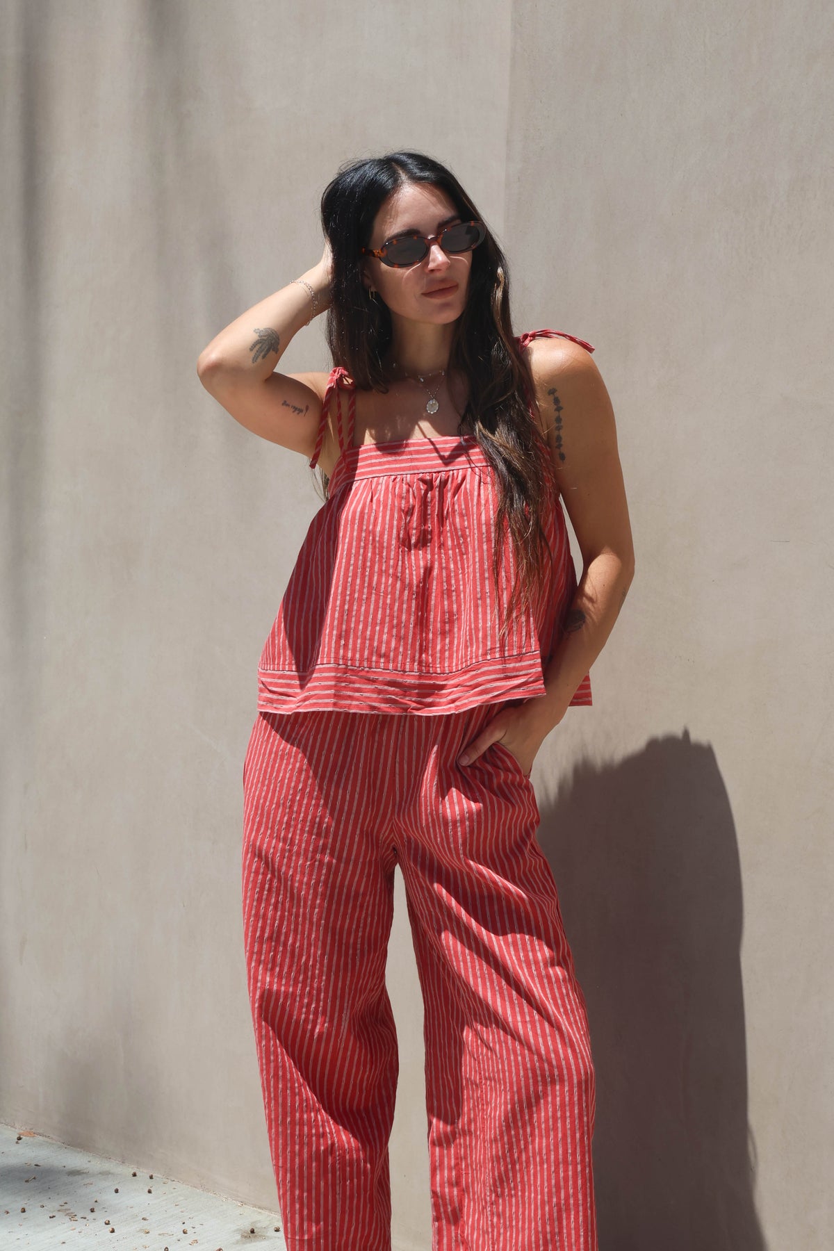 Woman wearing a red striped outfit against a plain wall