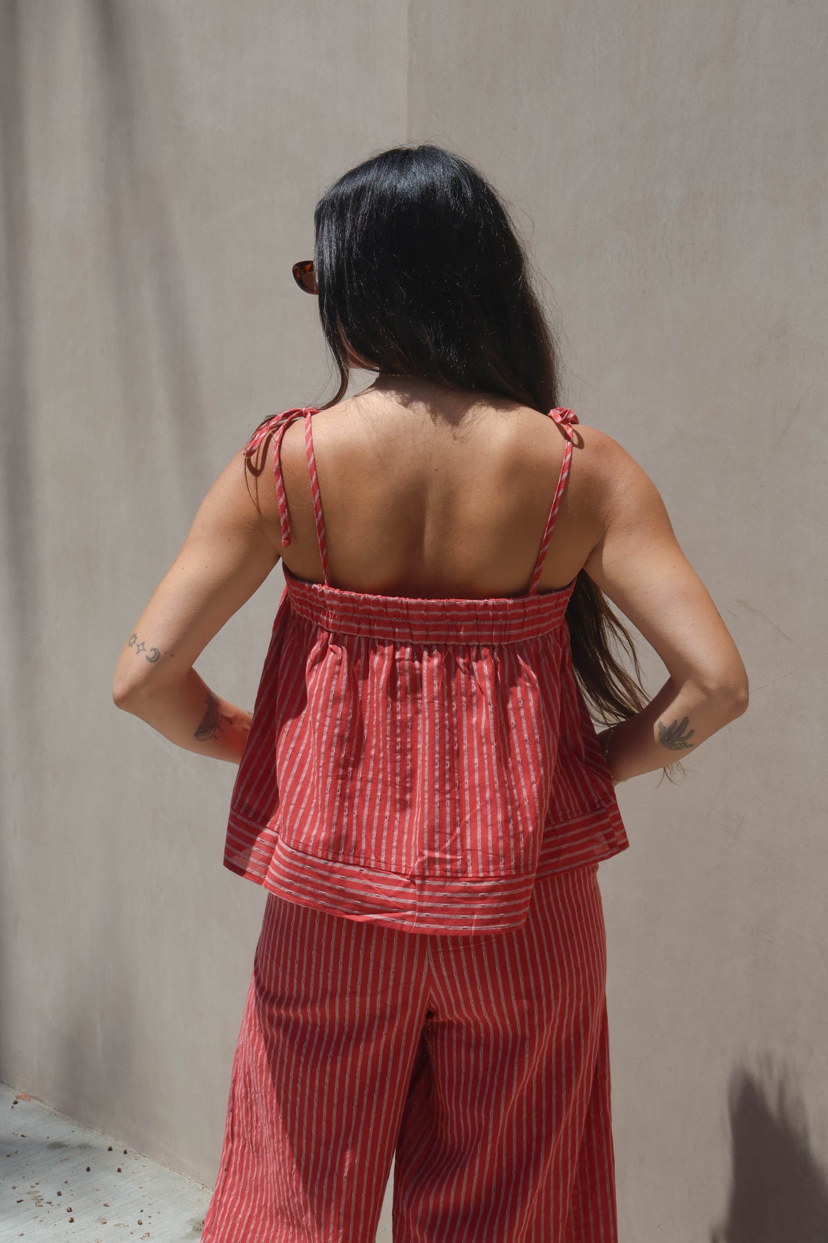 Woman wearing a red striped outfit against a beige wall