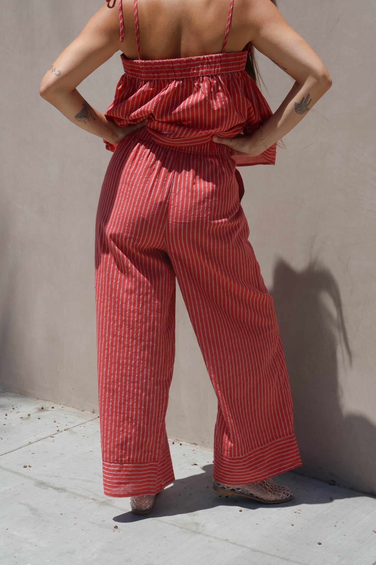 Person wearing a red striped outfit against a beige wall.