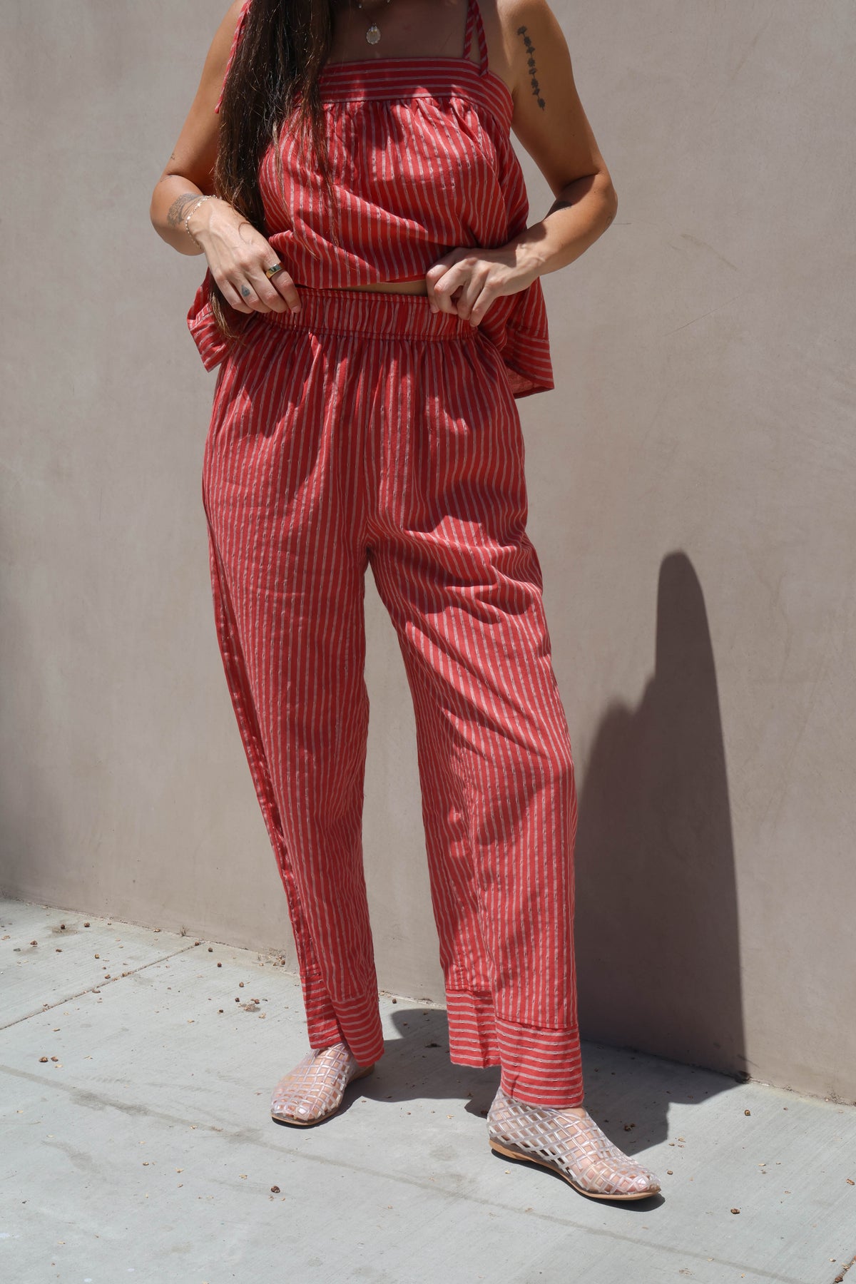 Person wearing a red striped outfit standing against a beige wall.
