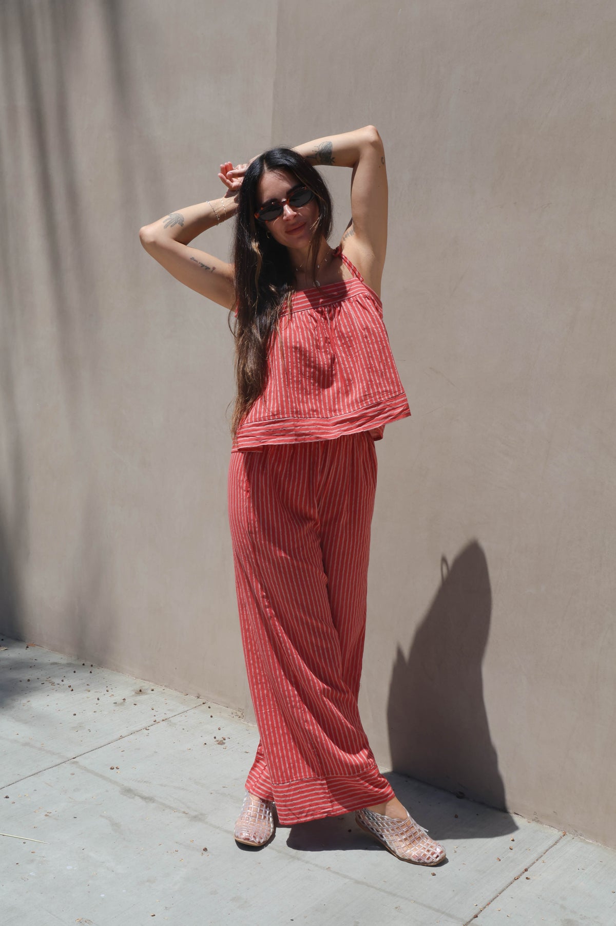 Woman in a coral outfit posing against a beige wall.