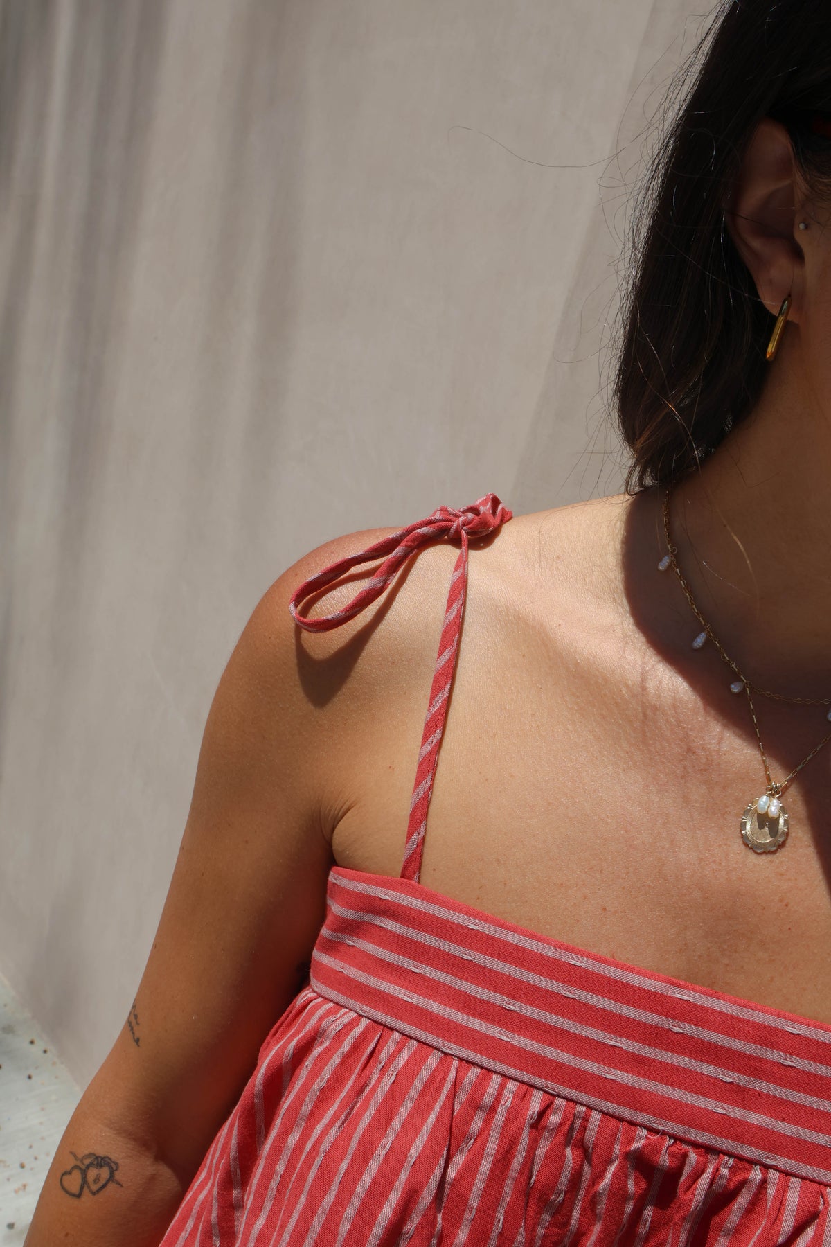 Person wearing a red and white striped dress with a neutral background