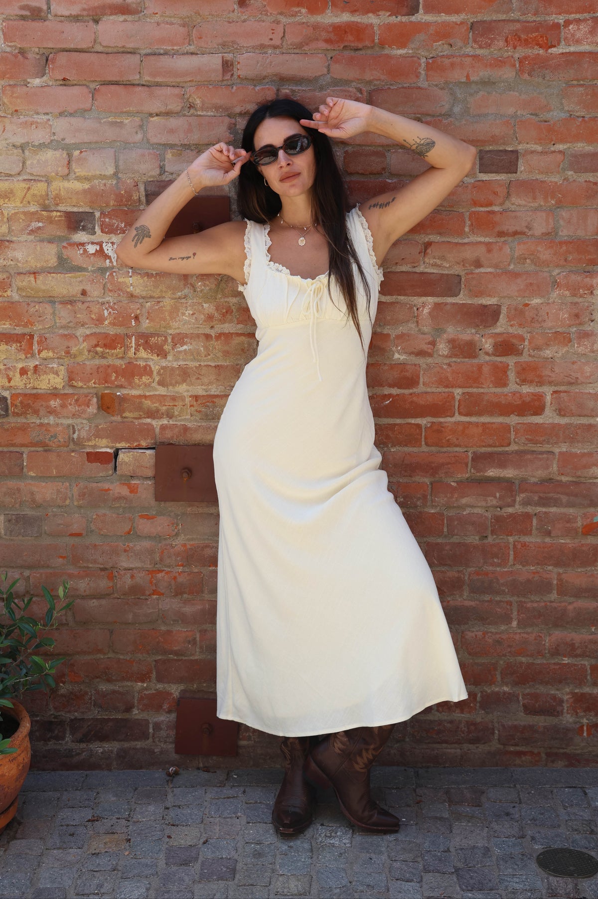 Woman in a white dress standing against a brick wall