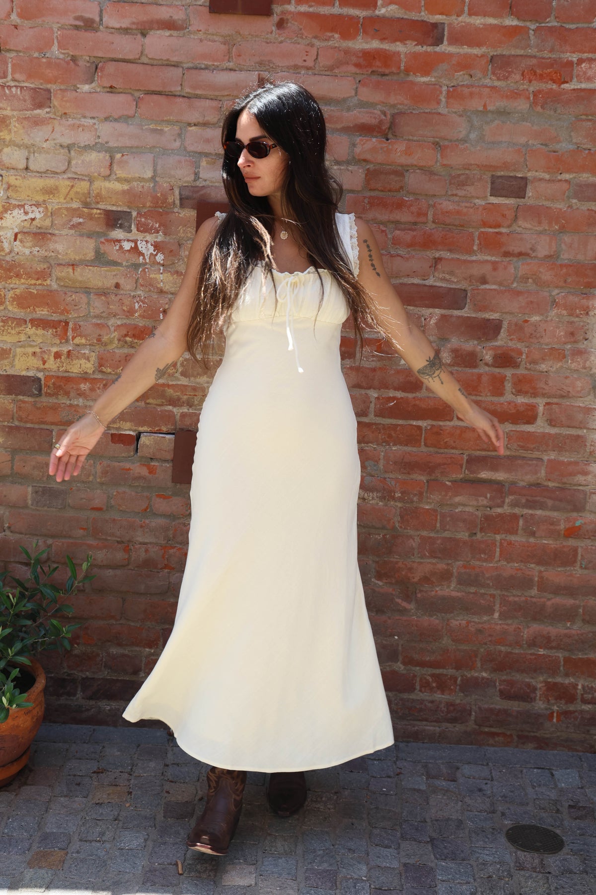 Woman in a white dress standing against a brick wall