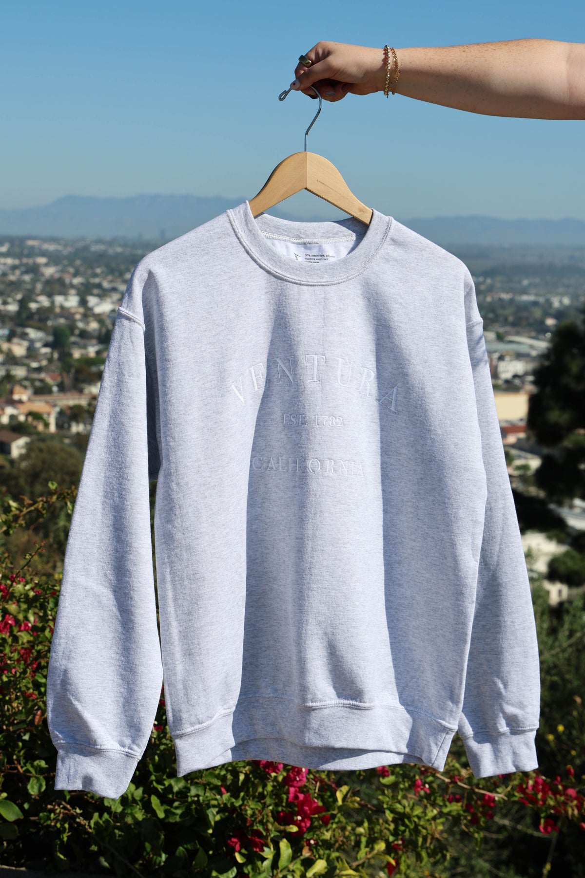 Light gray sweatshirt on a hanger with a scenic background