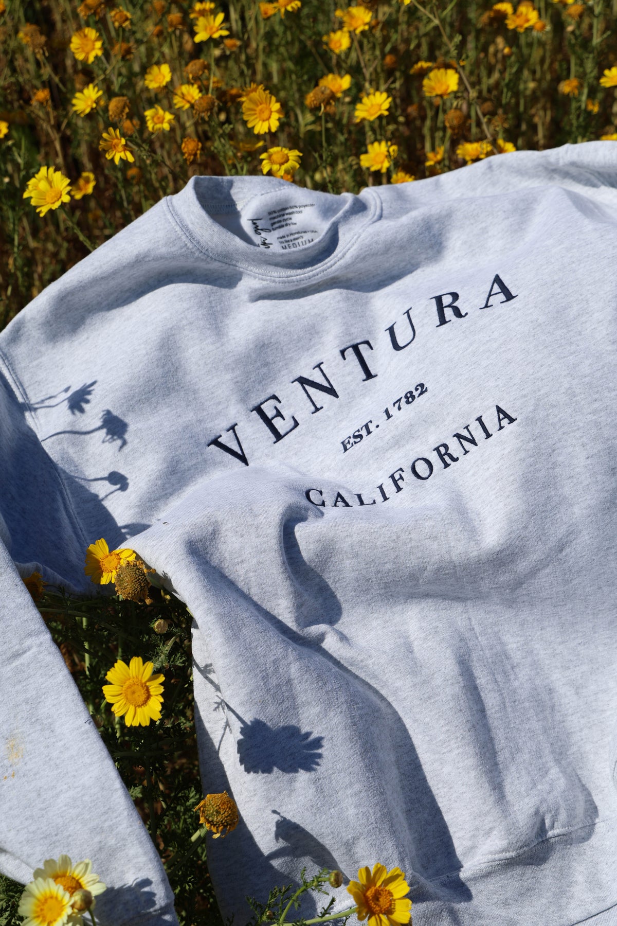 Gray sweatshirt with 'Ventura California' text on a background of yellow flowers