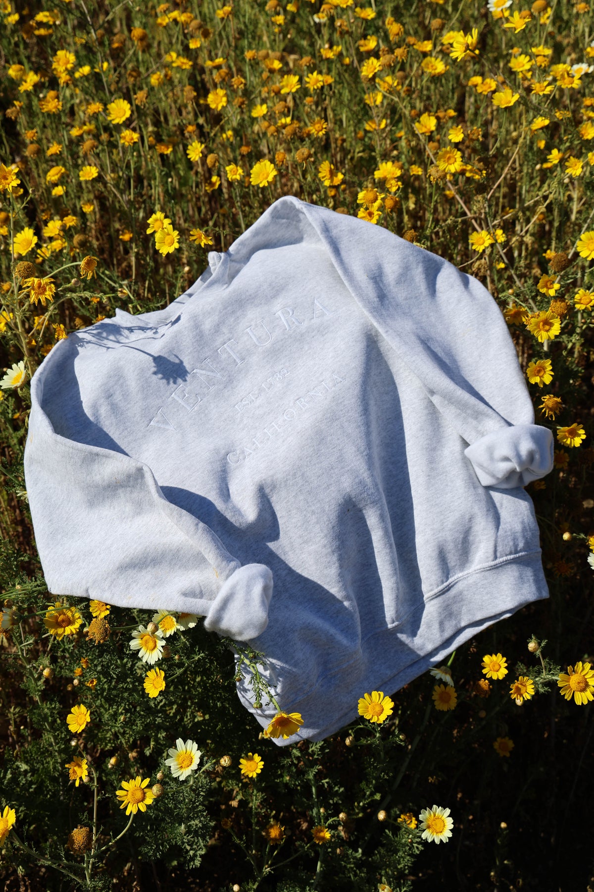 White/Ash Ventura Crewneck on a grassy field with yellow flowers