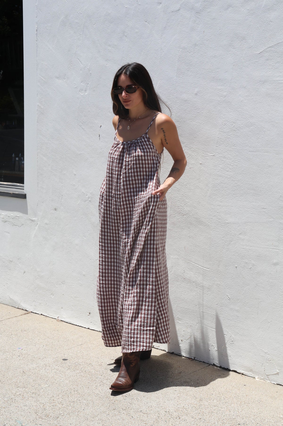 Woman in a checkered dress standing against a white wall.