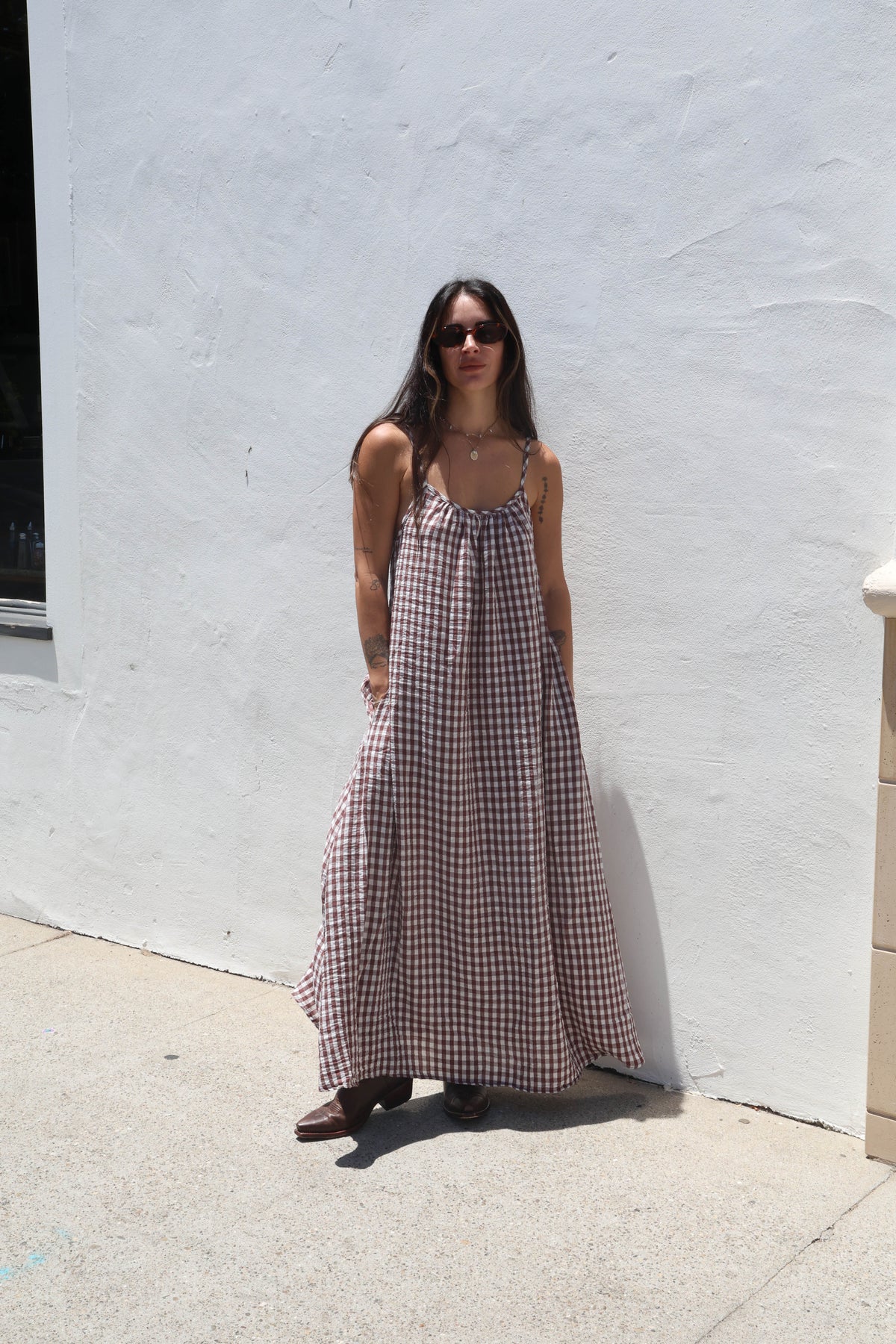 Woman in a checkered dress standing against a white wall.