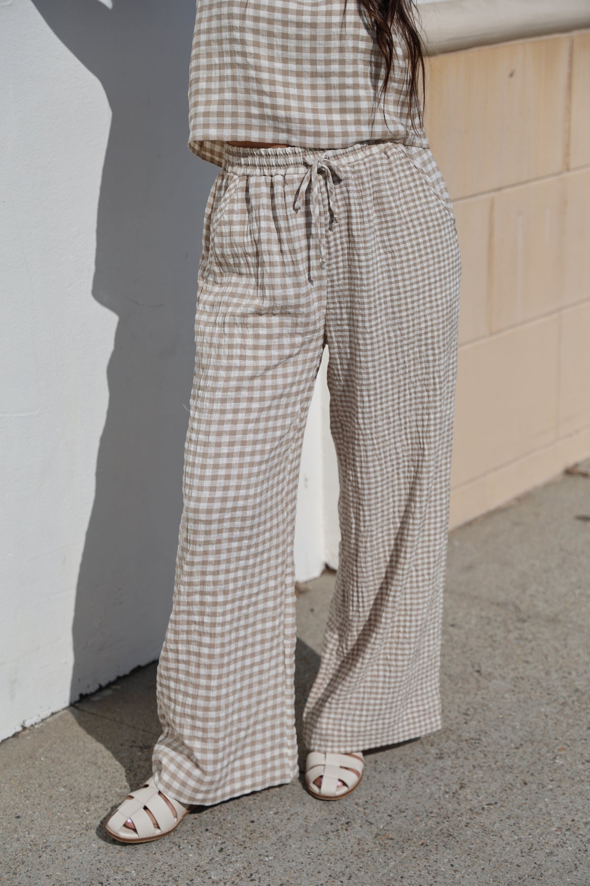 Person wearing checkered pants and sandals on a concrete floor.