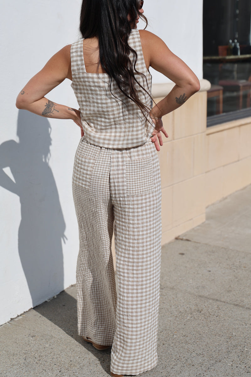 Woman in a checkered dress standing on a sidewalk with a building in the background
