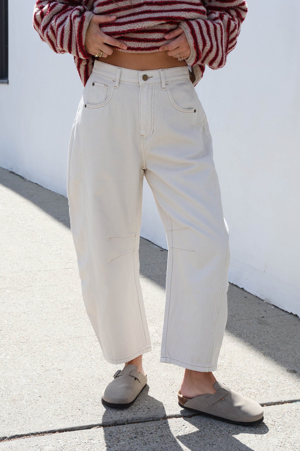 Woman wearing white jeans with a red and cream fleece.