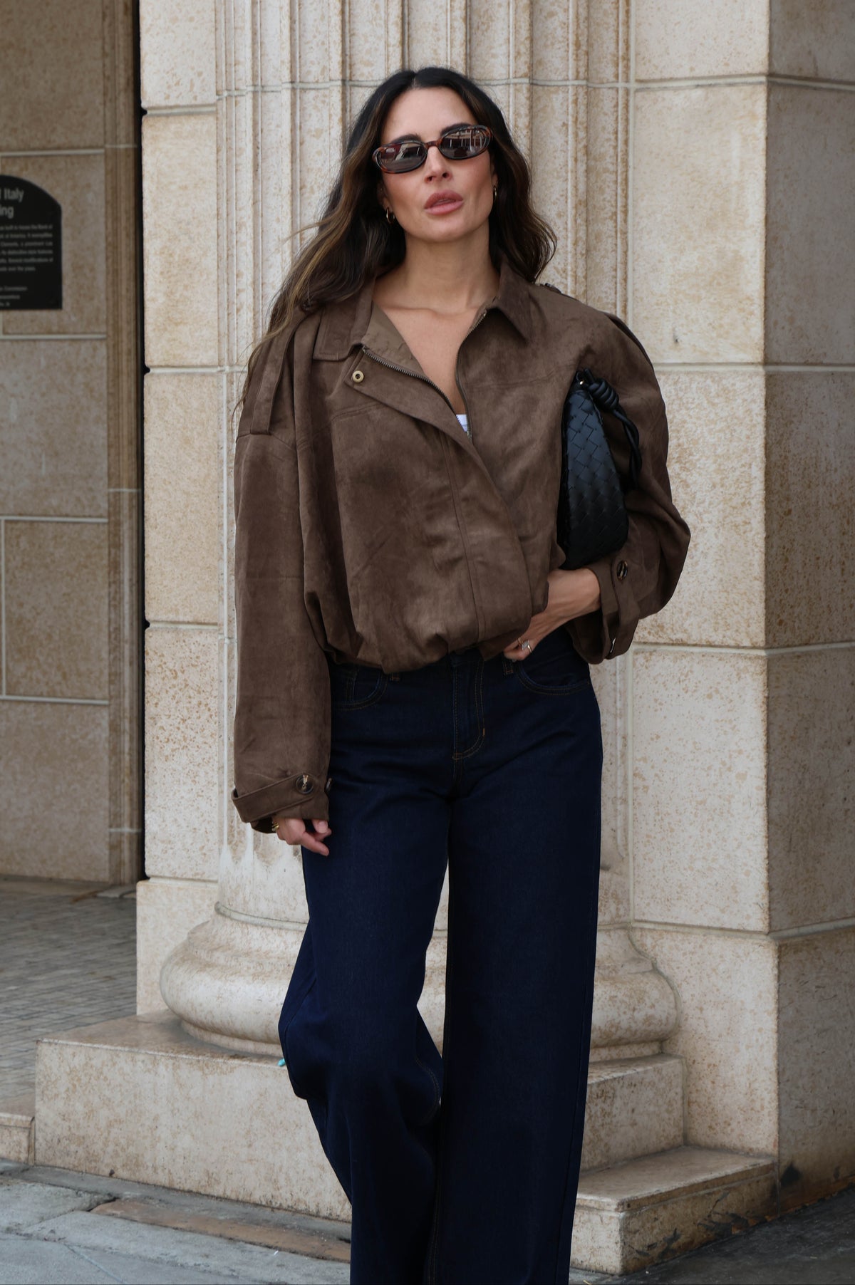 Woman wearing a brown suede jacket and dark jeans.