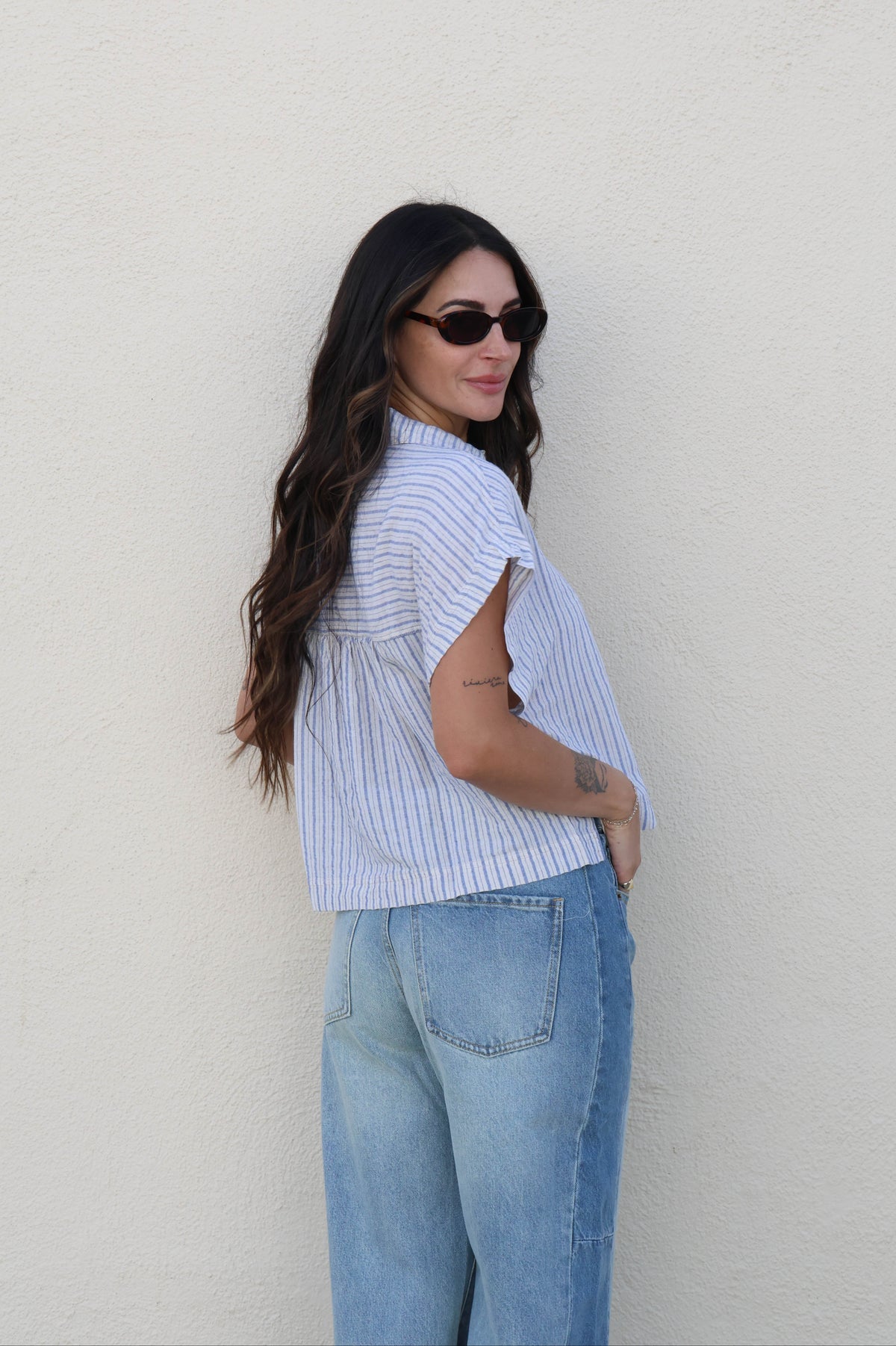 Woman wearing a striped shirt and jeans against a plain background