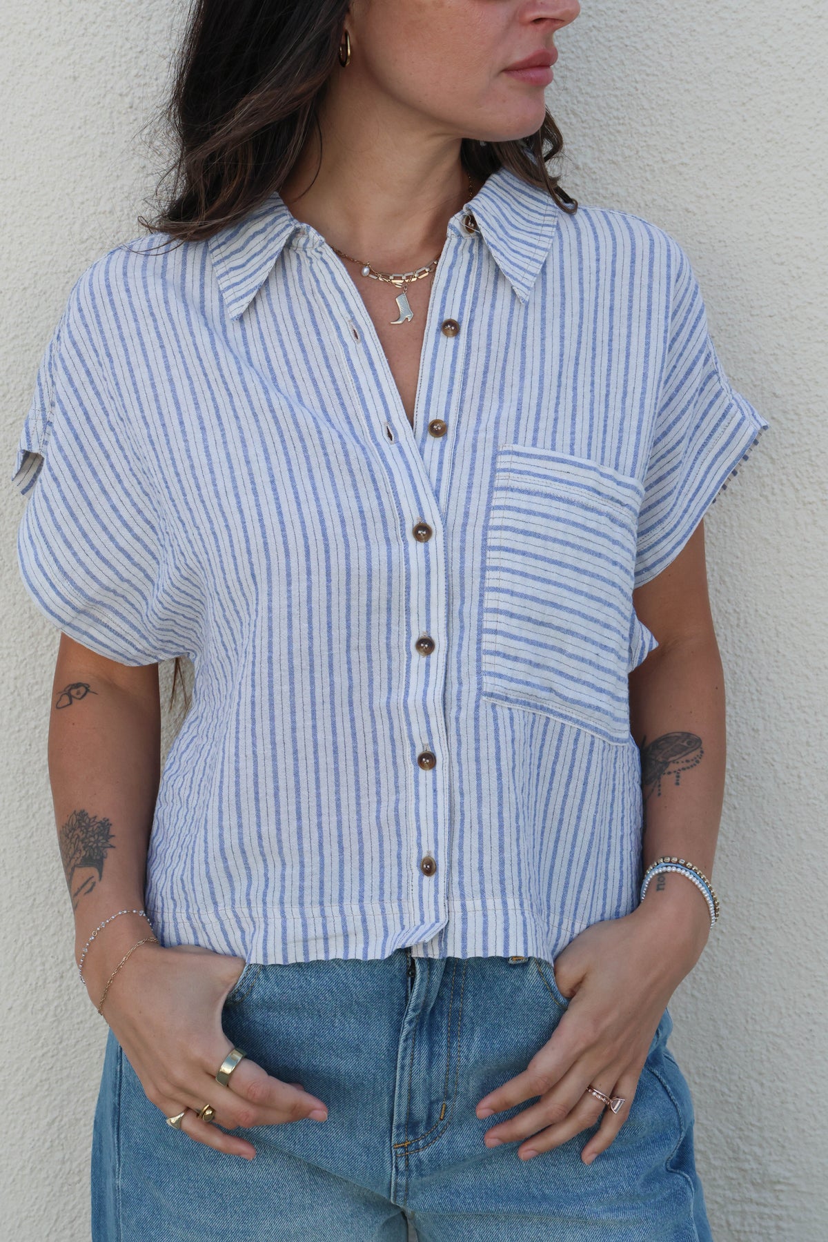 Woman wearing a blue and white striped shirt and jeans against a plain background