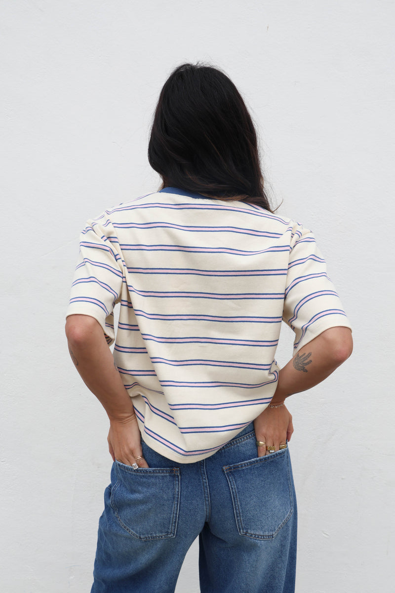 Person wearing a striped shirt and jeans with a plain background