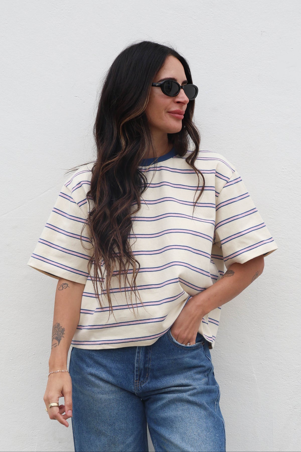 Woman wearing a striped shirt and sunglasses against a plain background