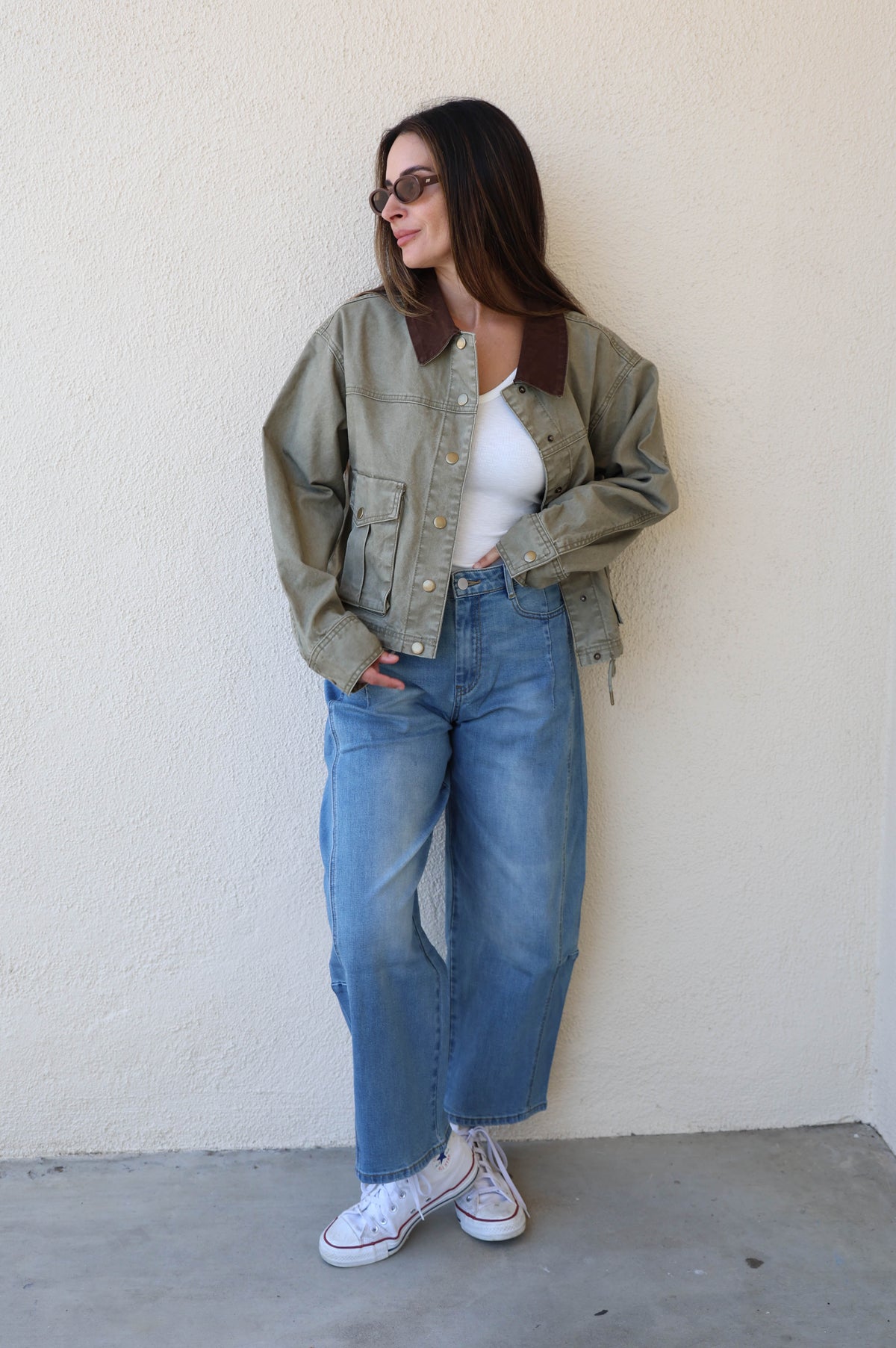 Woman modeling a pair of barrel jeans against a plain background.