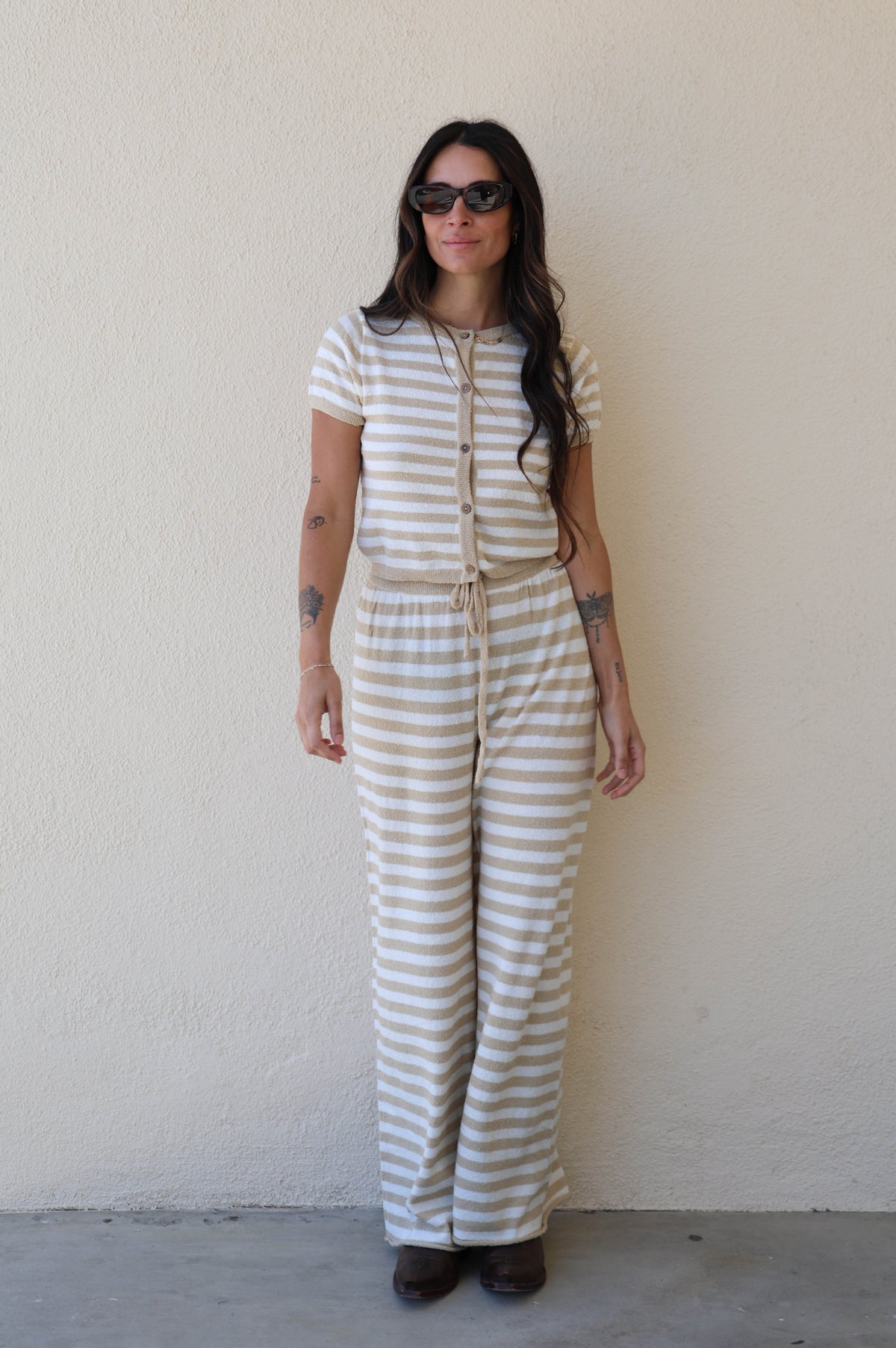 Woman wearing a striped jumpsuit against a plain white wall