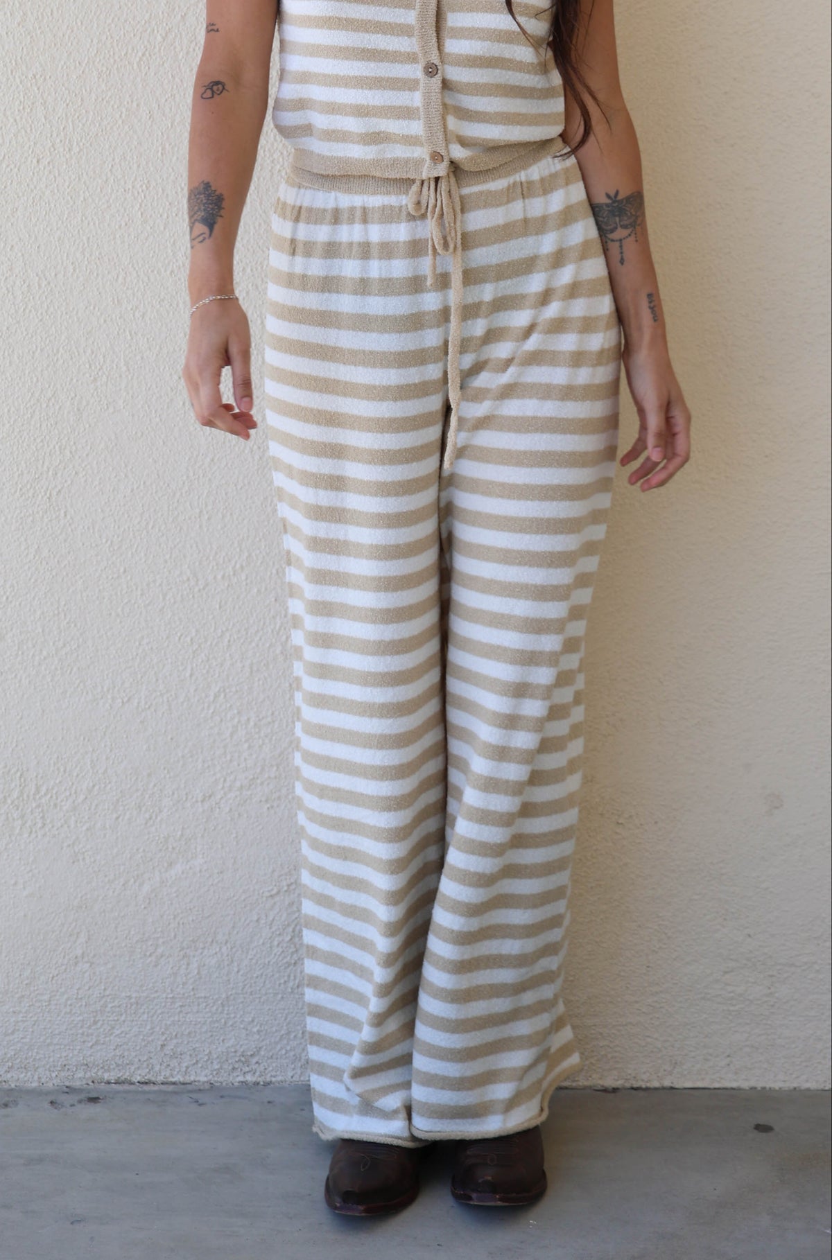 Woman wearing a striped jumpsuit against a plain white wall