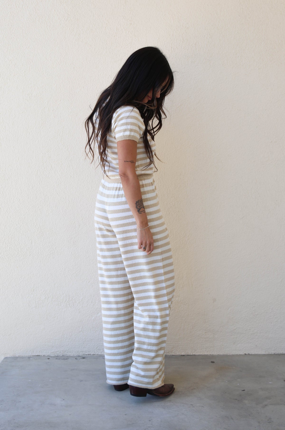 Person wearing a striped outfit standing against a white wall.