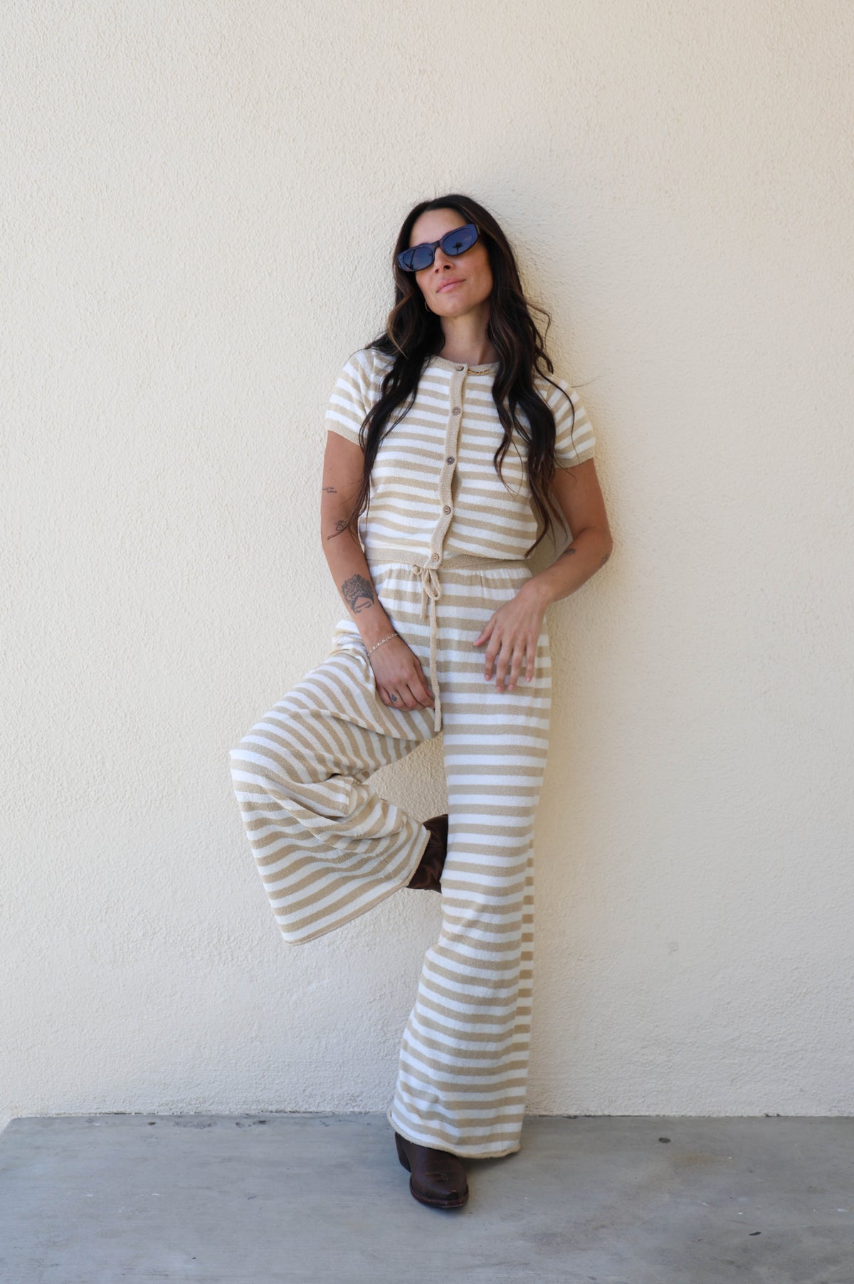 Woman wearing a striped outfit against a plain wall