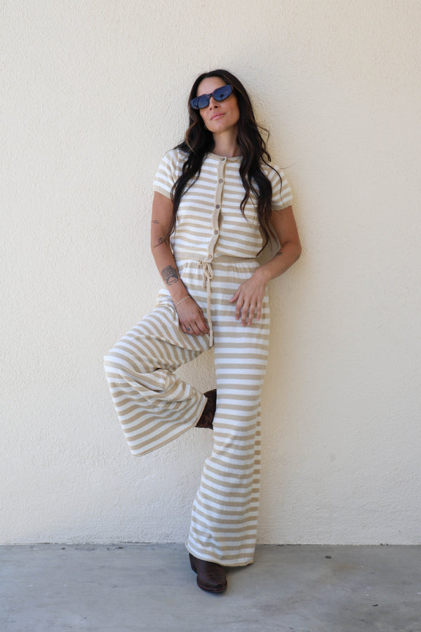 Woman wearing a striped outfit against a plain wall