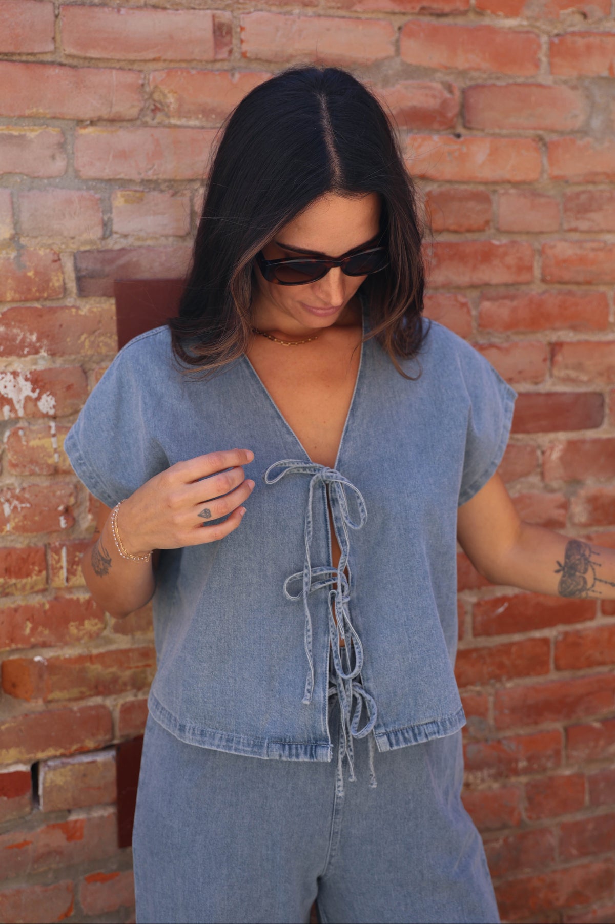Woman wearing a denim outfit against a brick wall