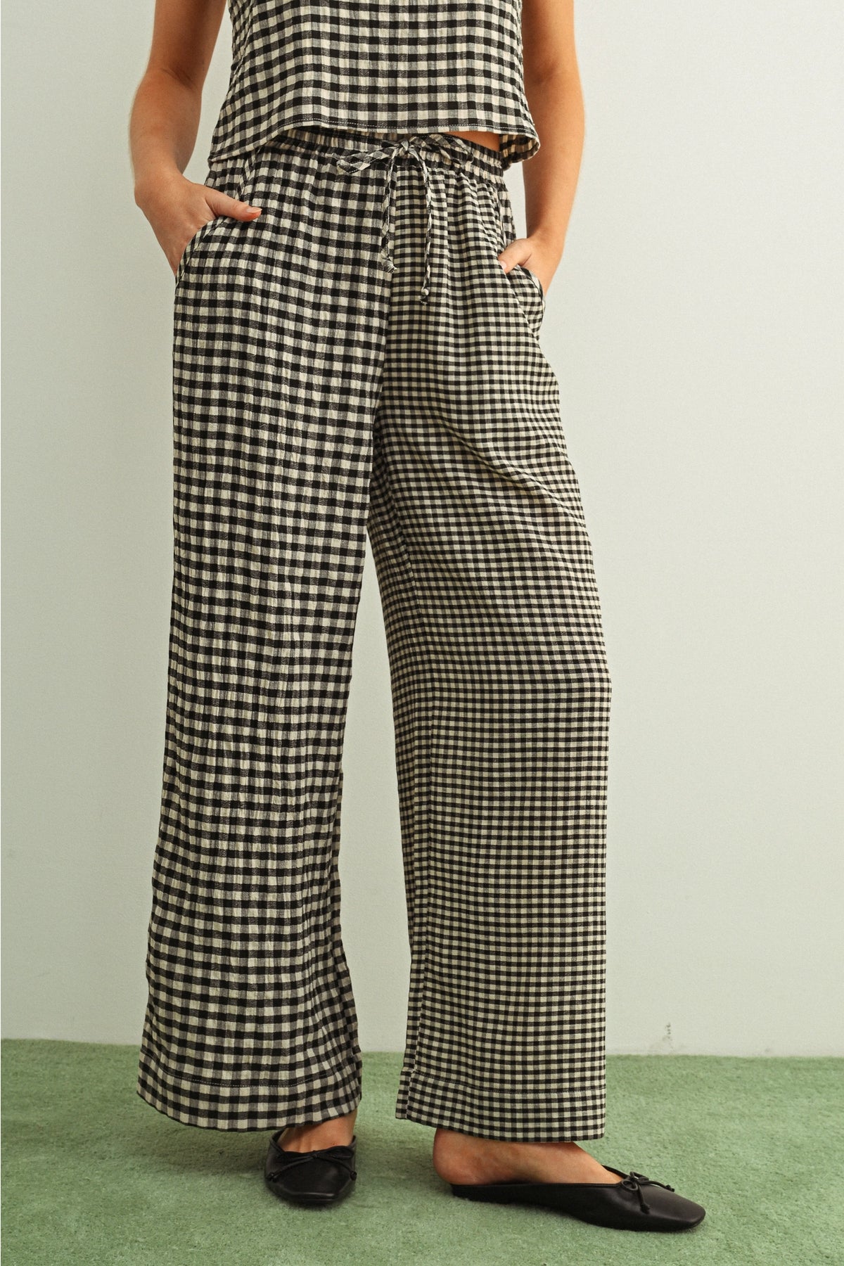 Person wearing black and white checkered pants on a plain background
