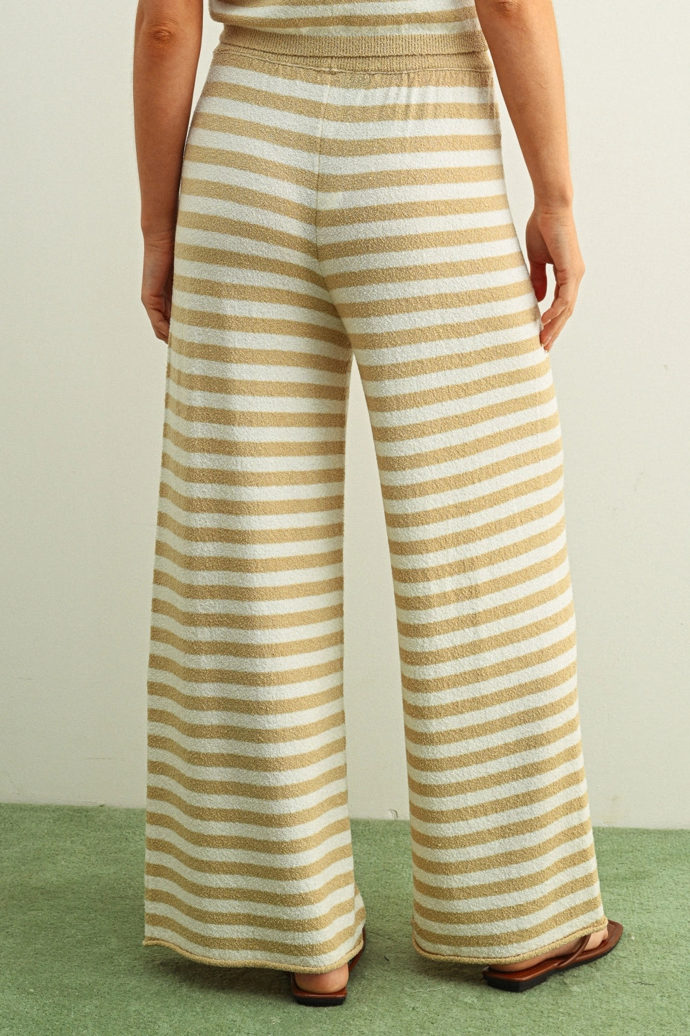 Person wearing yellow and white striped pants on a plain background