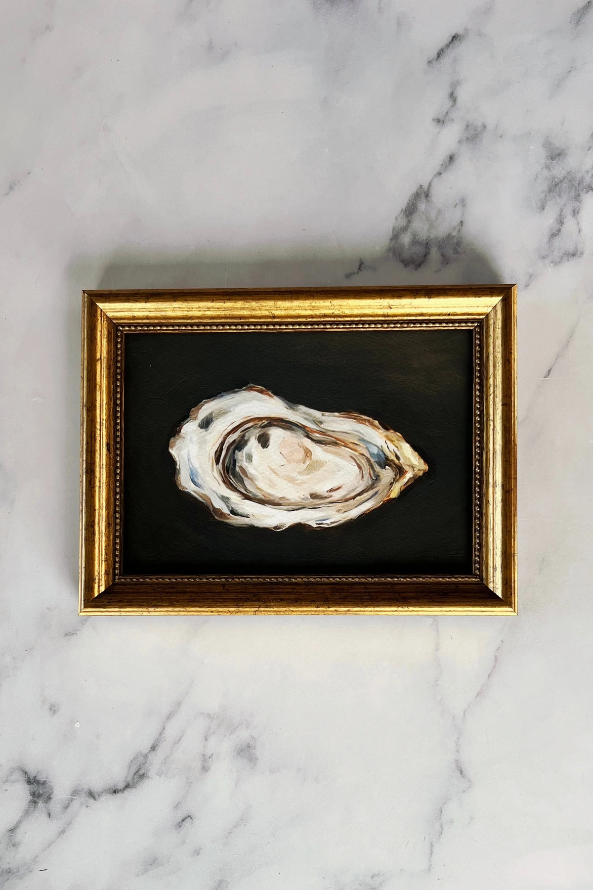 A framed Giclée print of an oyster on a marble surface.