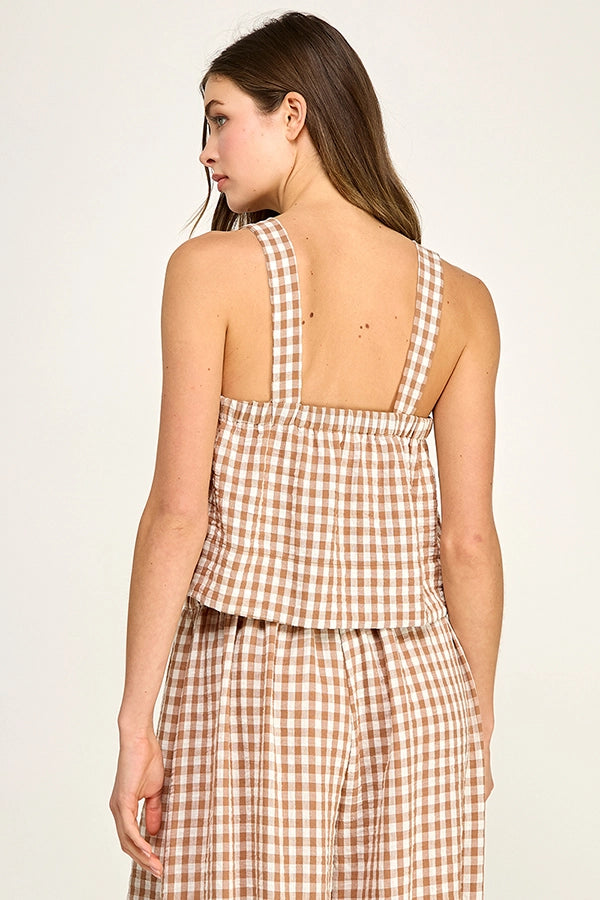 Woman wearing a brown and white checkered dress against a plain background
