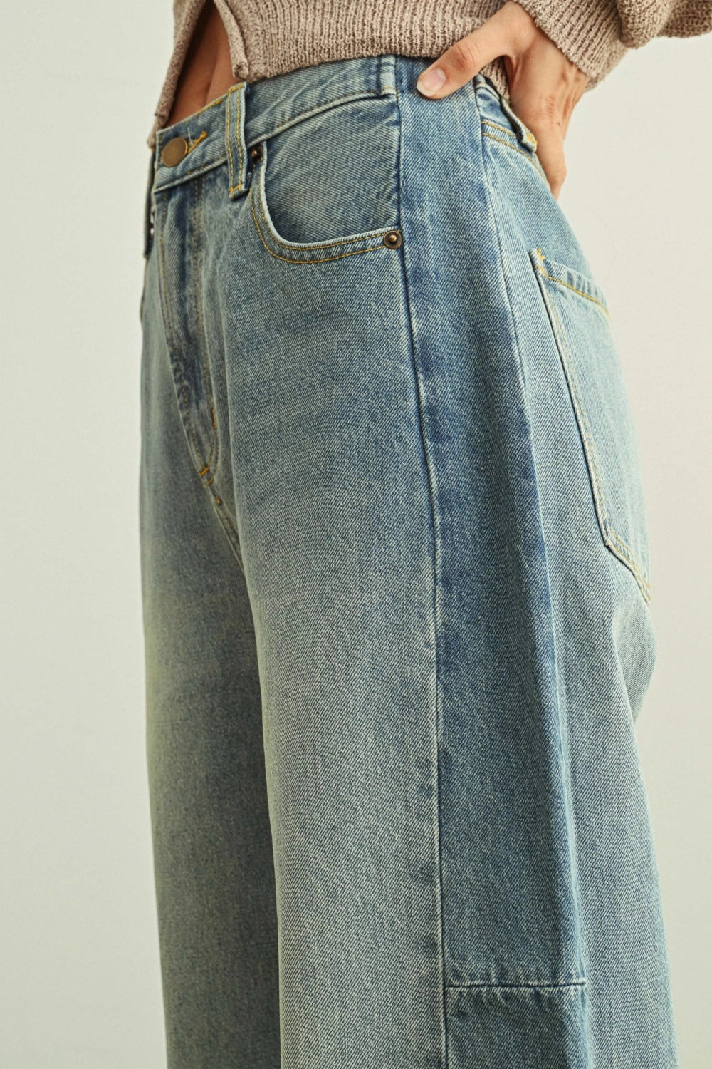 Blue jeans worn by a person on a plain background