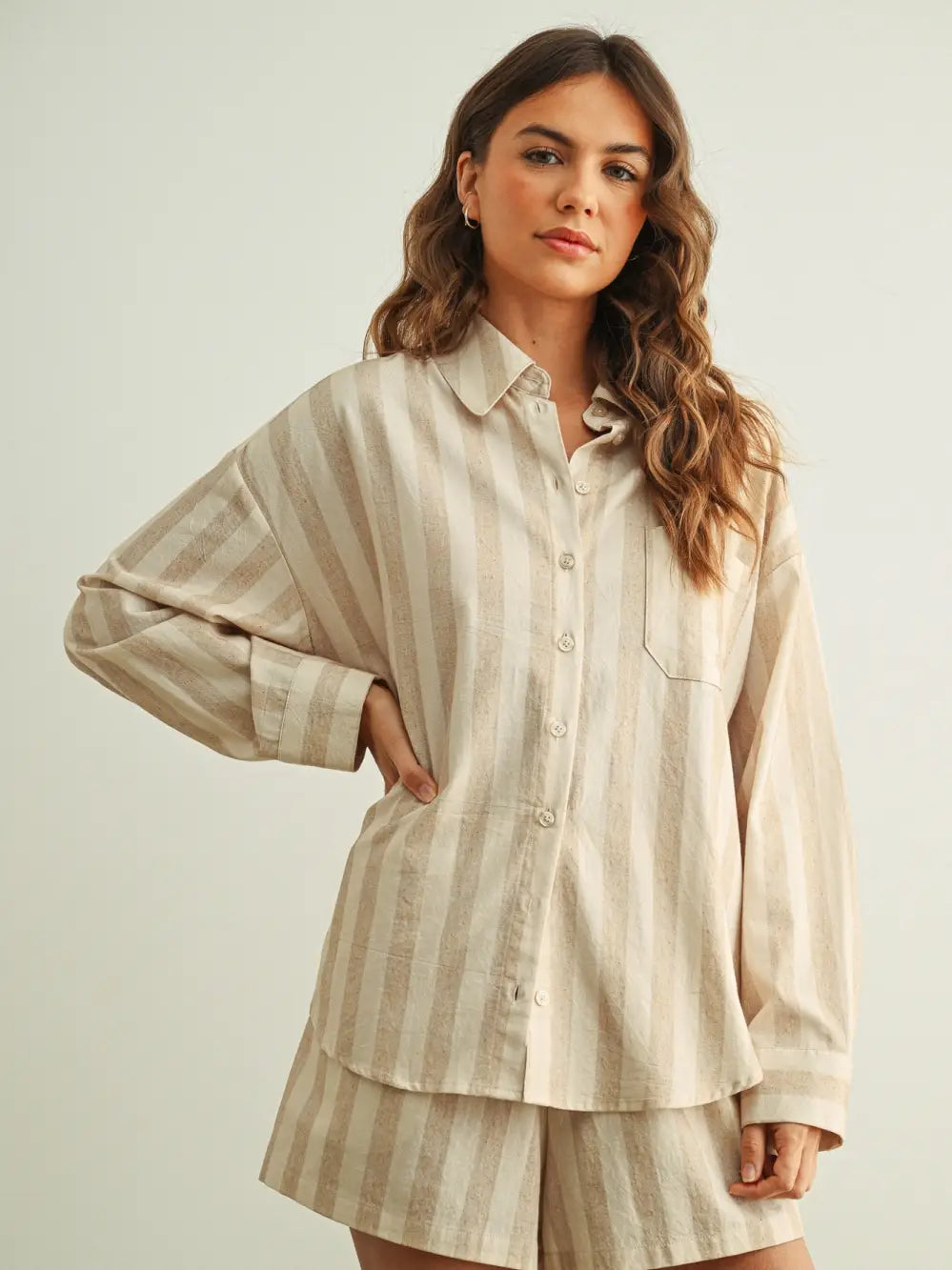 Woman wearing a beige striped shirt and shorts set against a plain background